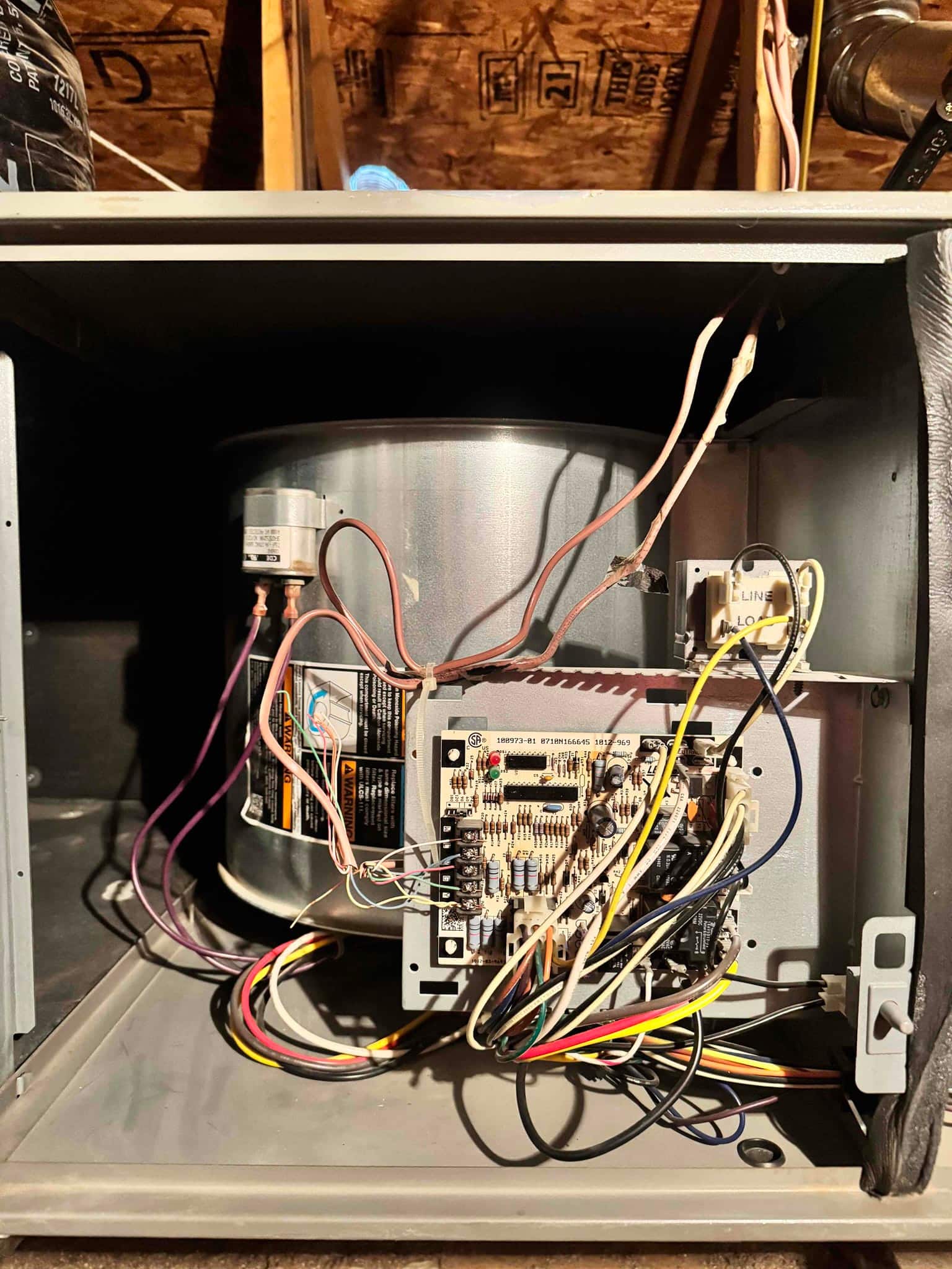 Open air handler cabinet showing blower housing, control board with multiple low-voltage wires, and mounted relay during repair.