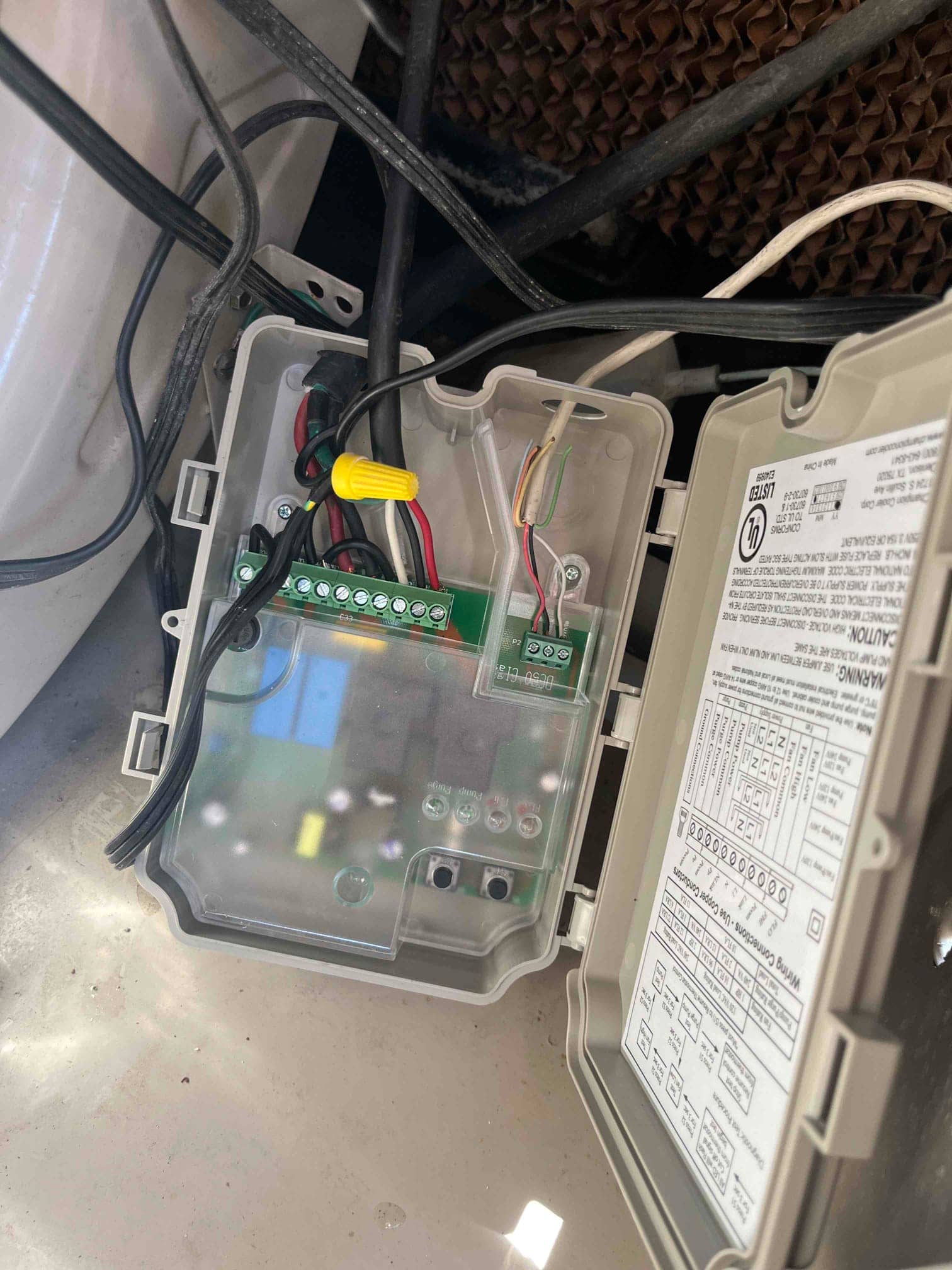 Open evaporative cooler control box shows wired terminal strip, relays, and wiring diagram inside the cover.