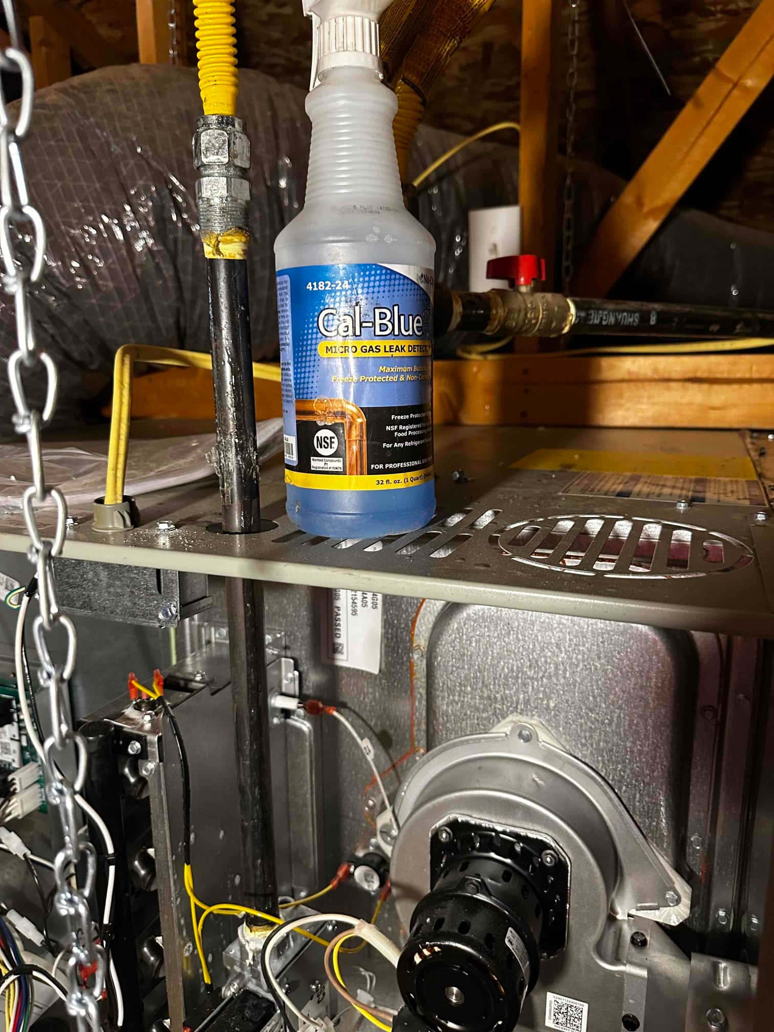 Open furnace cabinet with inducer assembly and wiring visible; gas piping and leak detection solution bottle placed on top panel.
