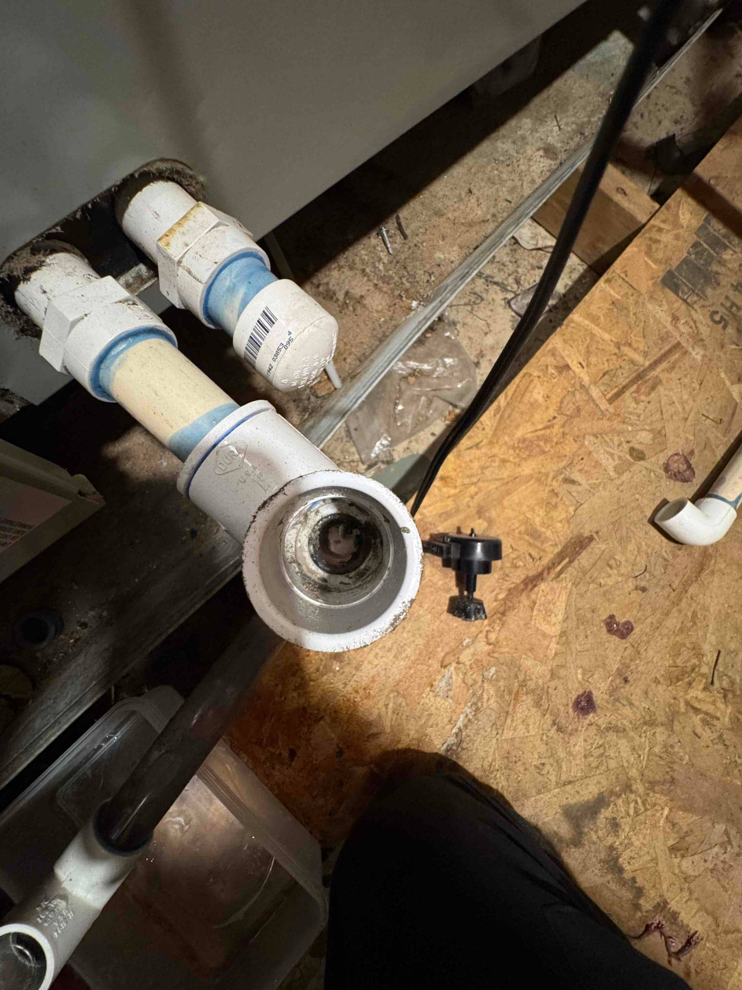 Open PVC condensate drain cleanout at the air handler shows debris inside the fitting during drain line cleaning.