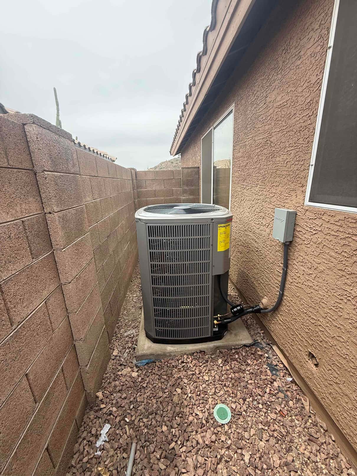 Outdoor heat pump condenser set on a level pad with insulated refrigerant lines and weatherproof electrical disconnect installed.