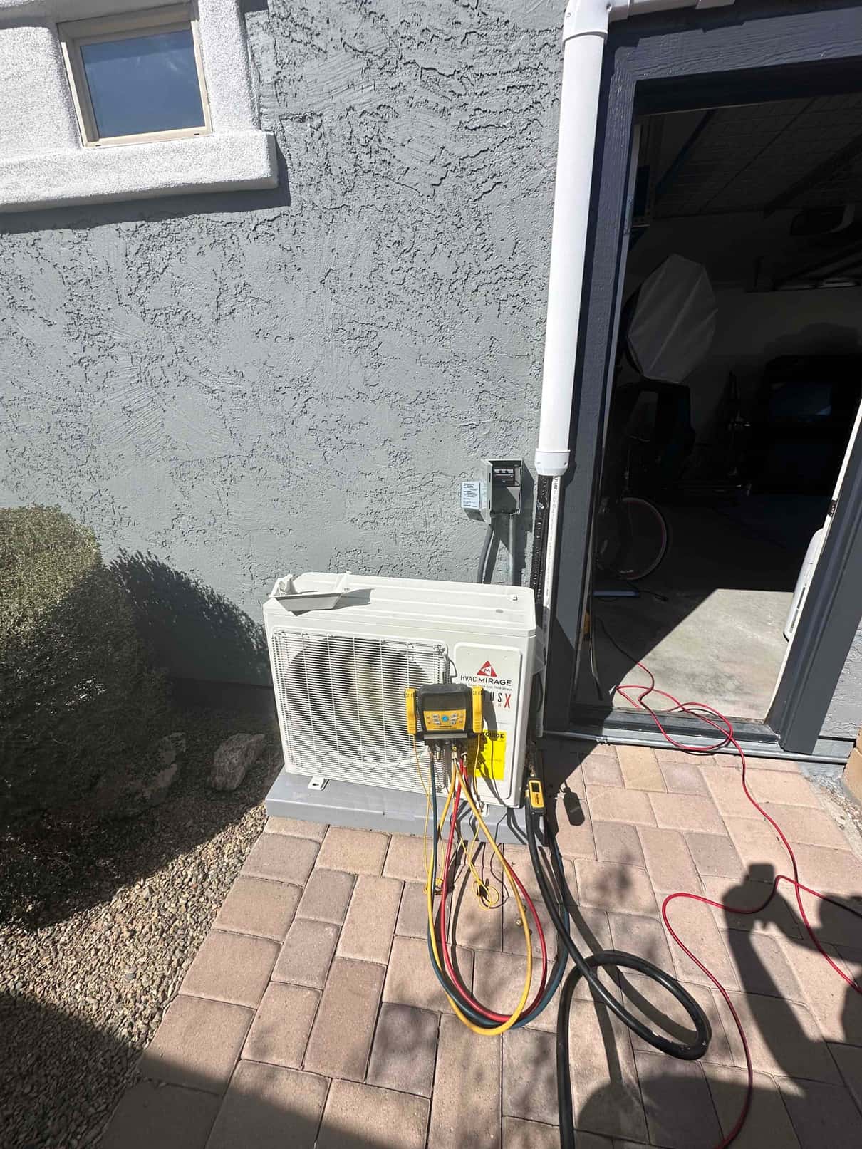 Outdoor mini-split condenser set on a level pad with line set and digital manifold connected during commissioning.