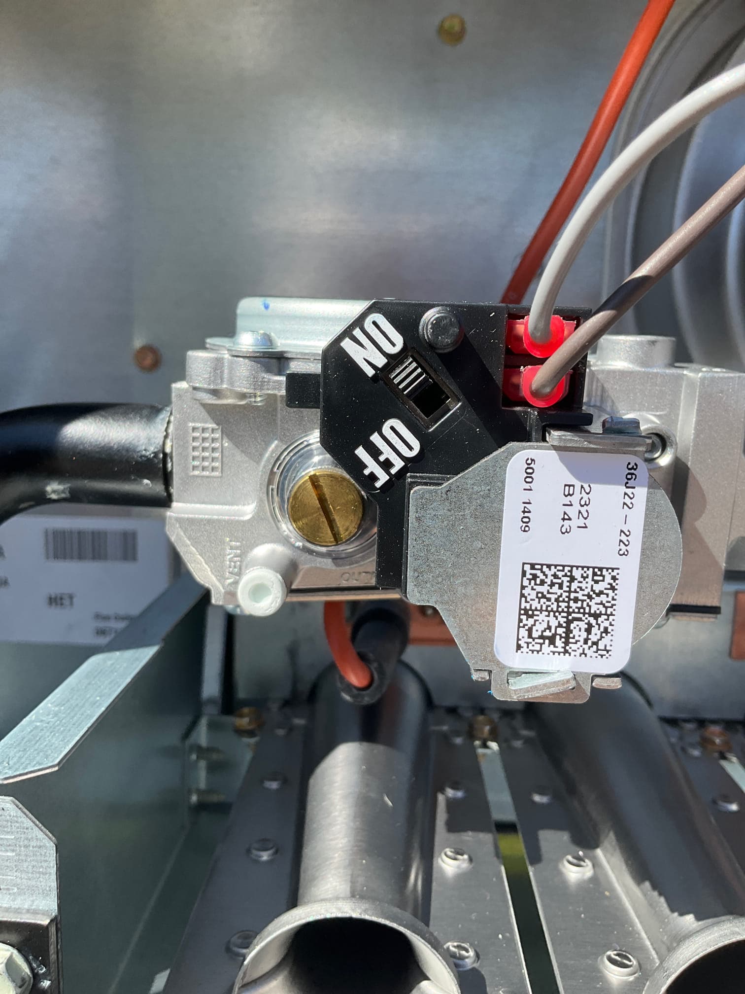 Close-up of a furnace gas valve with ON/OFF selector and wiring connections above the burner manifold.