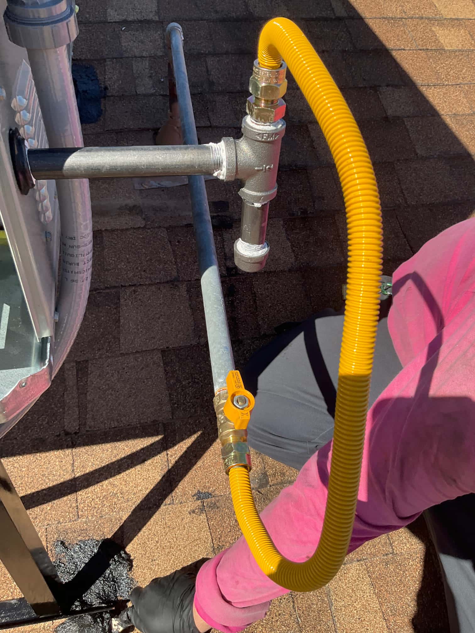 Flexible yellow gas connector with shutoff valve ties into black iron pipe at rooftop package unit connection.