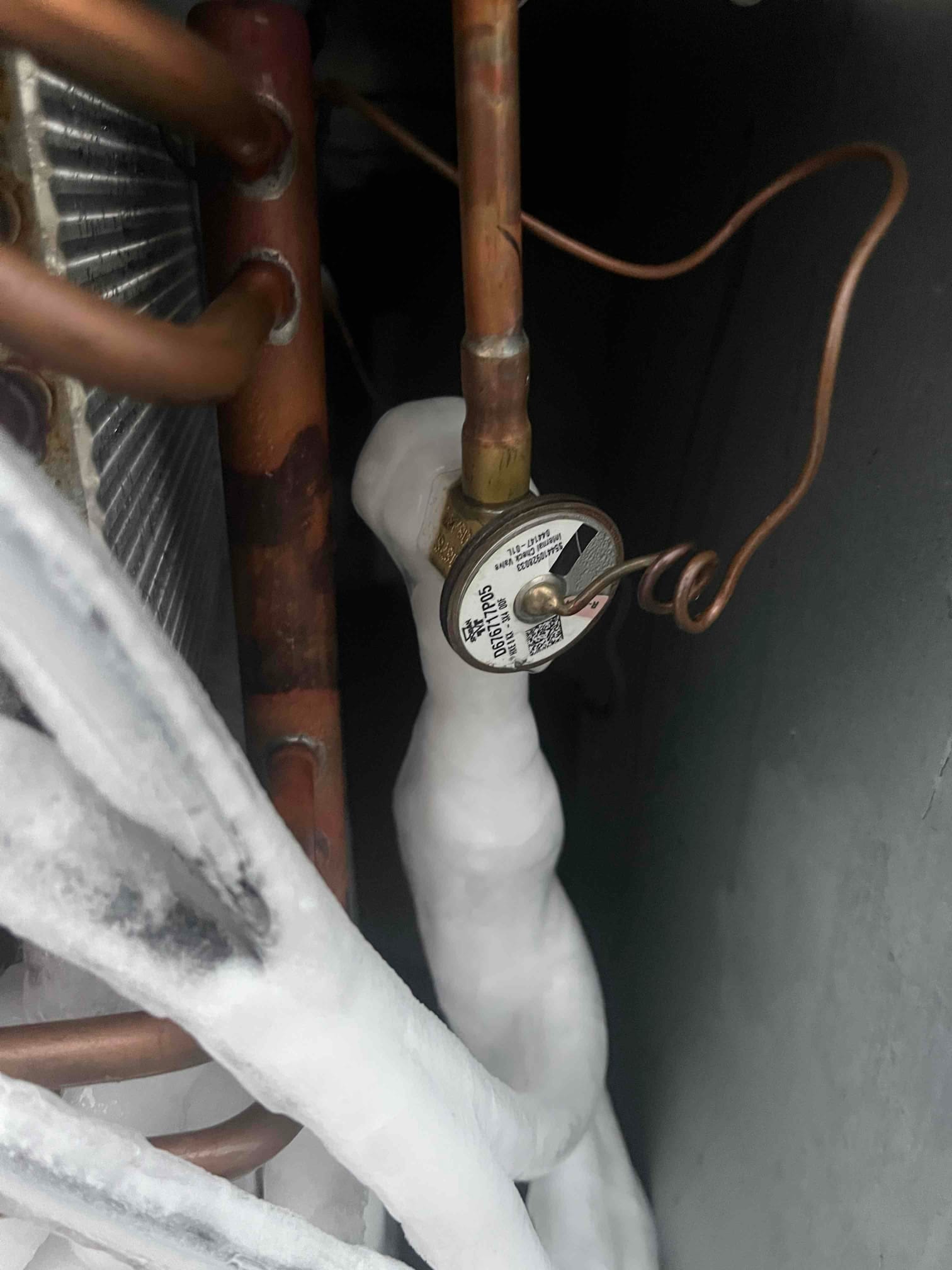 Iced suction line and frost-covered tubing near the evaporator coil, with a frost-covered service valve visible.