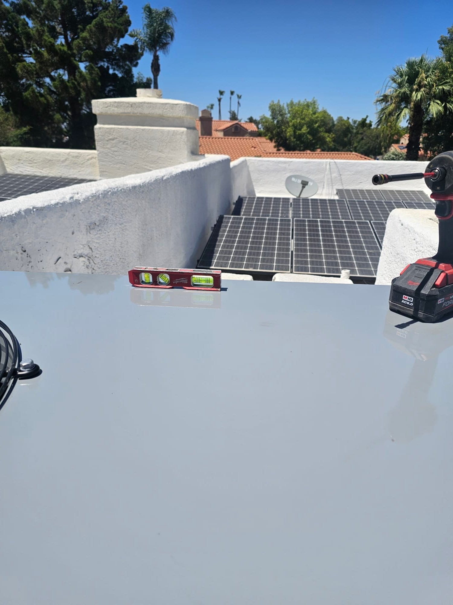 Level placed on top of a rooftop package unit during installation, with tools and solar panels visible in the background.