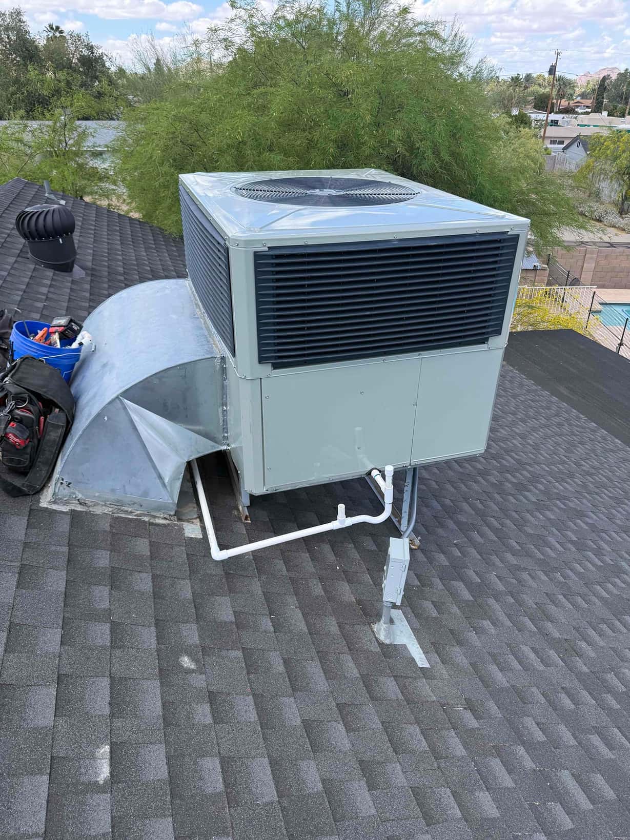 New rooftop package unit installed on curb with sealed duct transition, insulated condensate drain, and weatherproof electrical disconnect.