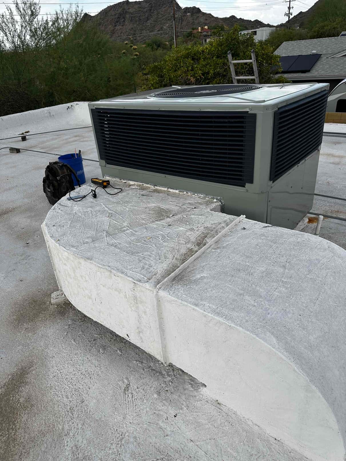 New rooftop package unit set and connected to sealed rooftop duct curb, with tools staged nearby for commissioning.