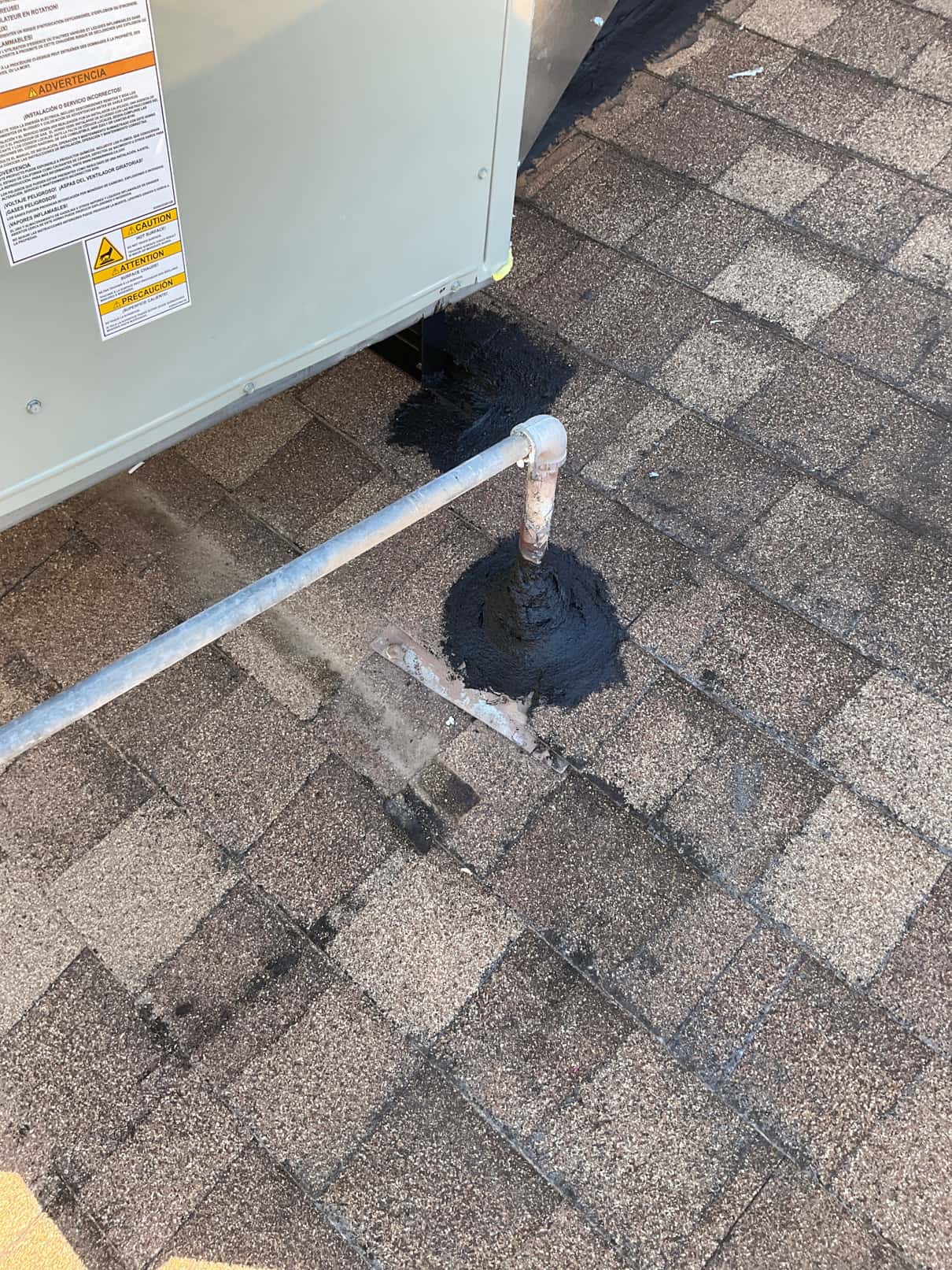 Rooftop package unit set with sealed roof penetration and supported condensate or drain piping secured beside the cabinet.