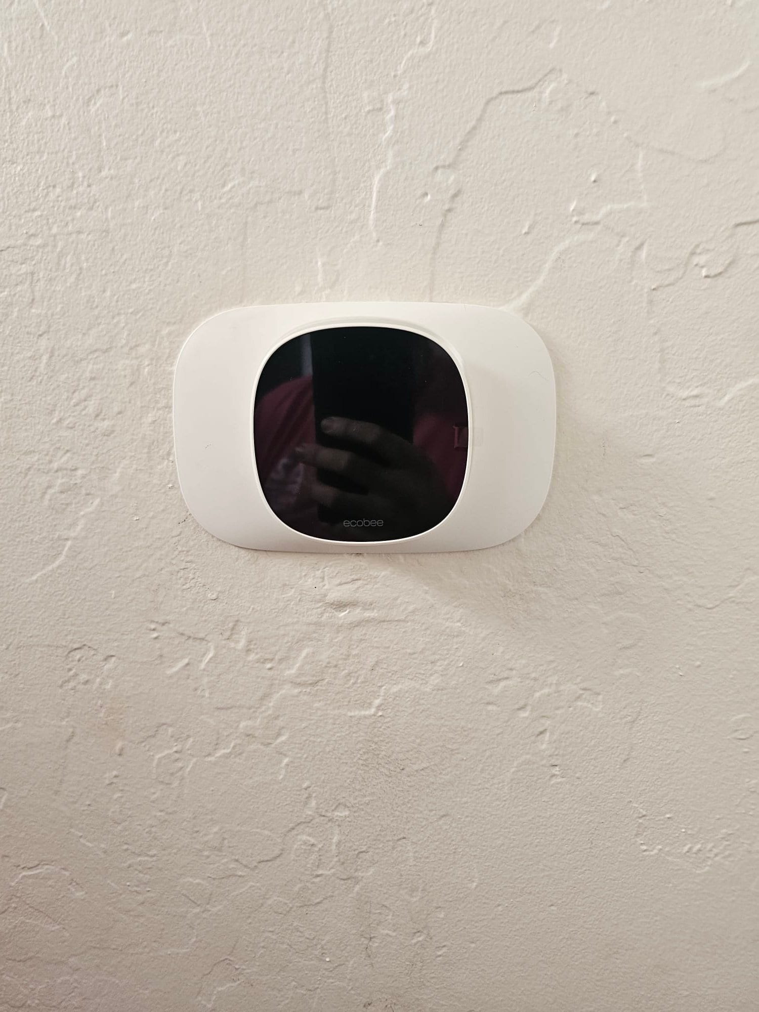 Wall-mounted smart thermostat installed on a finished wall, completing the control interface for the new HVAC system.