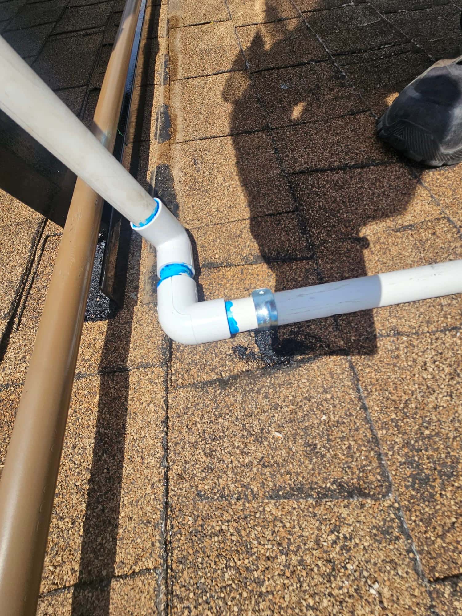 PVC condensate drain piping on rooftop with solvent-welded fittings and coupling, routed alongside a line set cover.