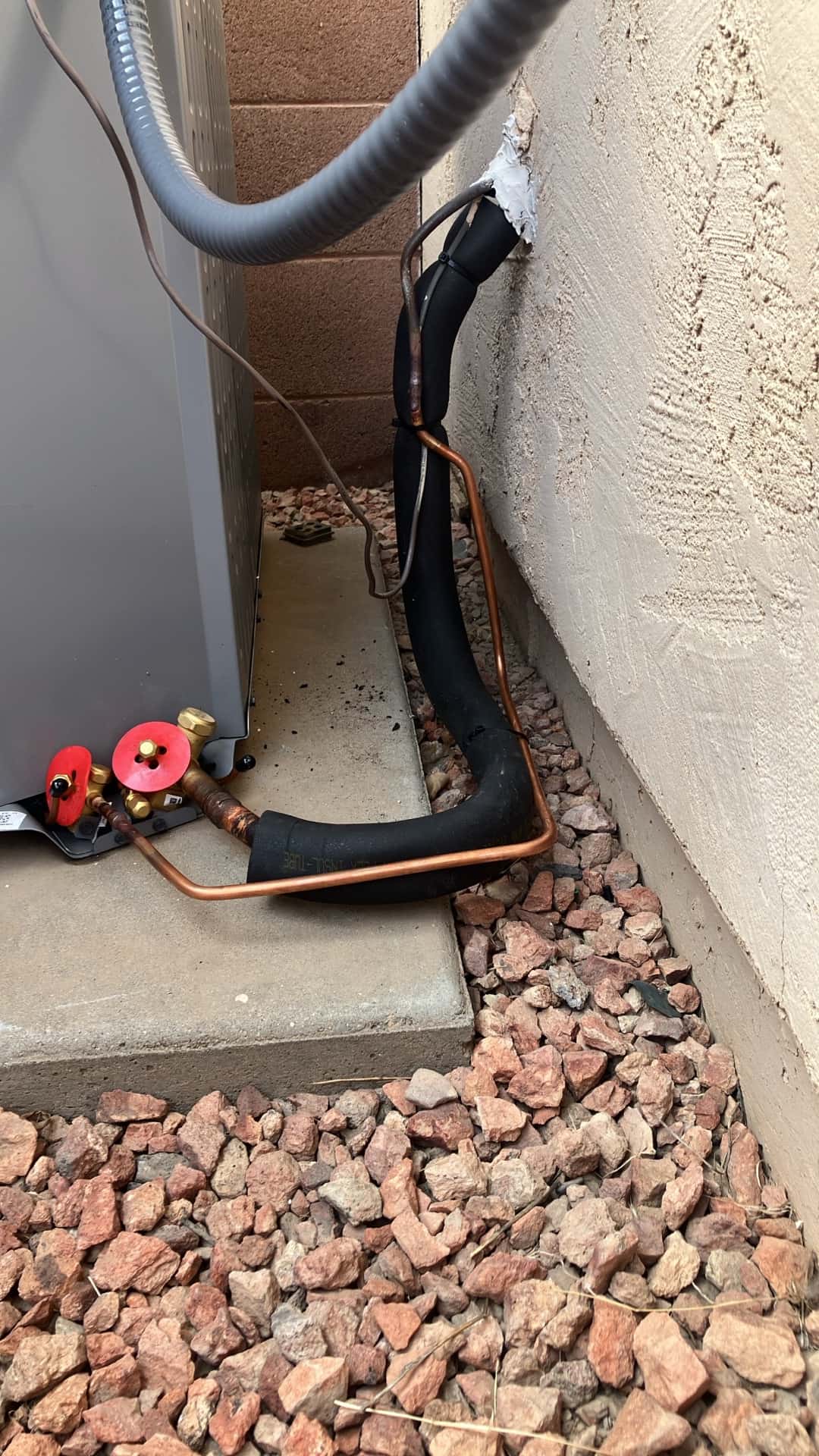 Refrigerant line set and insulation routed from wall penetration to the outdoor unit service valves, with sealed entry and tidy bends.