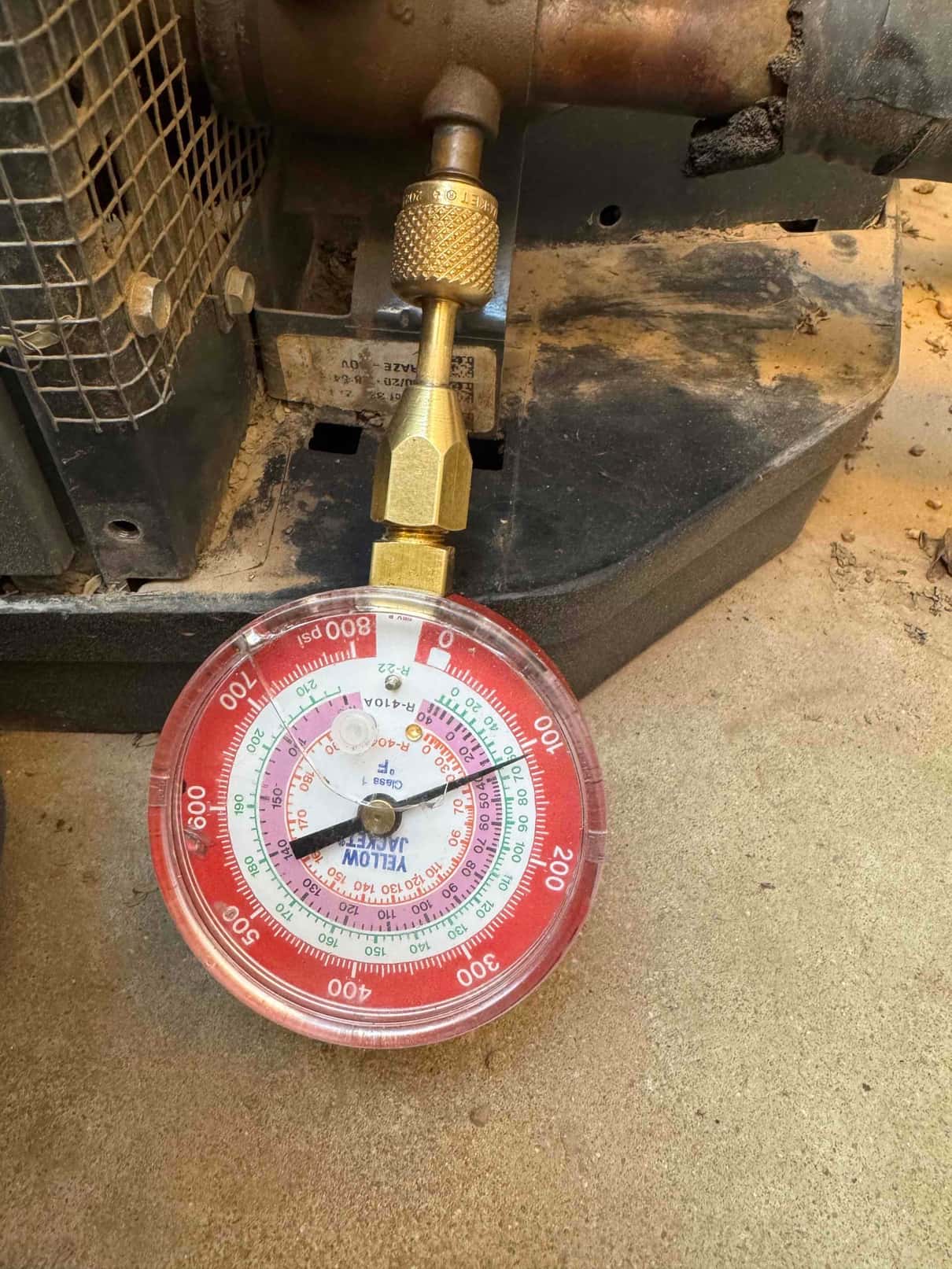 Refrigerant manifold gauge connected to the service port at the outdoor unit during air conditioning diagnostics.