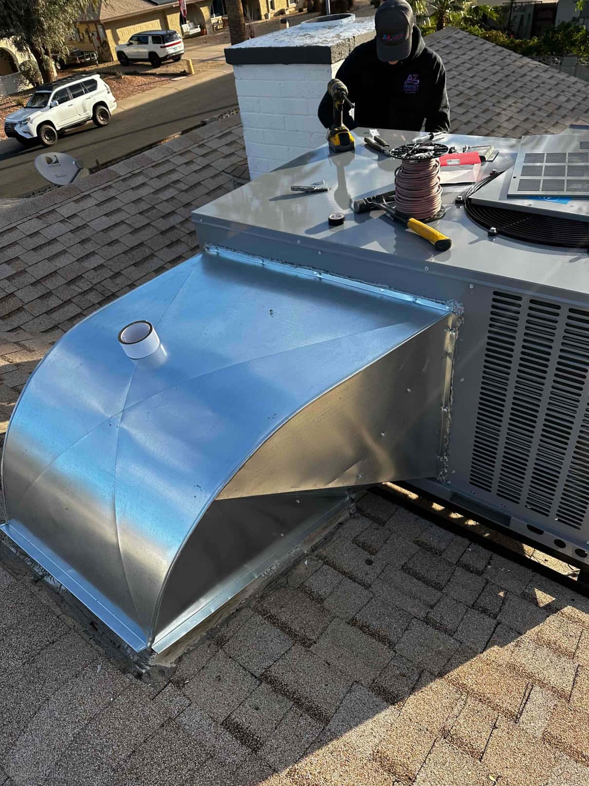 Rooftop package unit set with new sheet metal curb adapter and sealed duct connection during installation work.