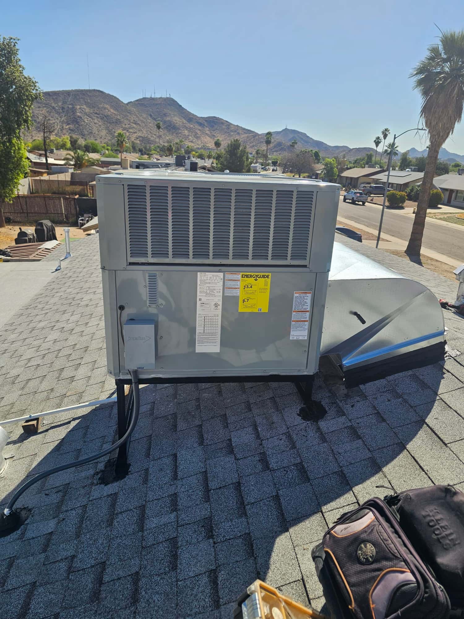 Rooftop packaged HVAC unit newly installed on stands with sealed roof penetrations and connected electrical conduit and duct transition.