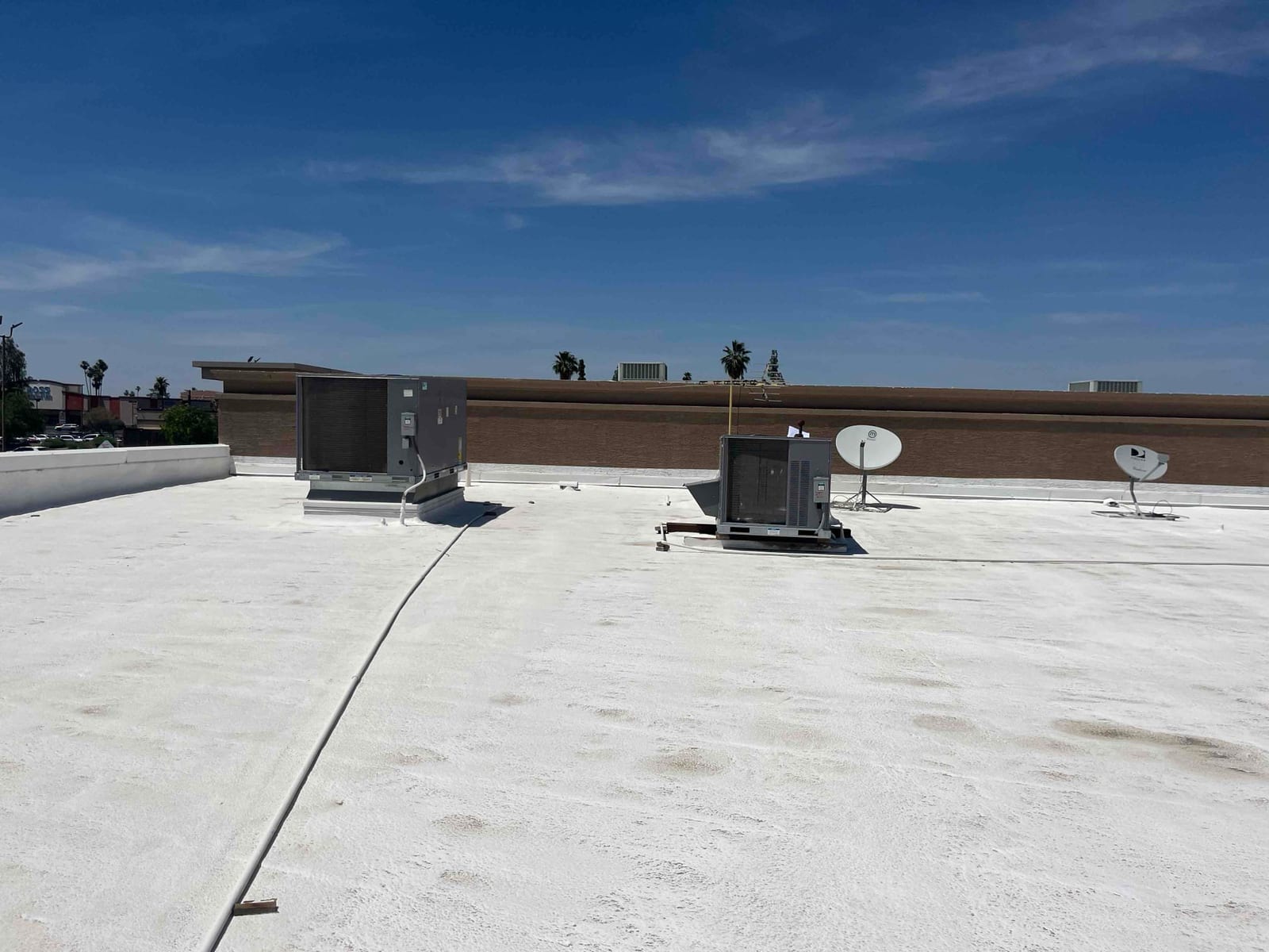Rooftop packaged HVAC units on a flat white roof with condenser sections and service access panels visible under clear sky.