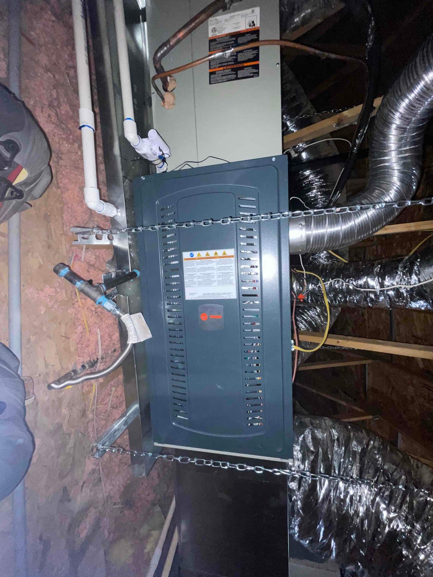 Suspended furnace and evaporator assembly installed with condensate piping, flexible gas connector, and insulated supply and return duct connections.