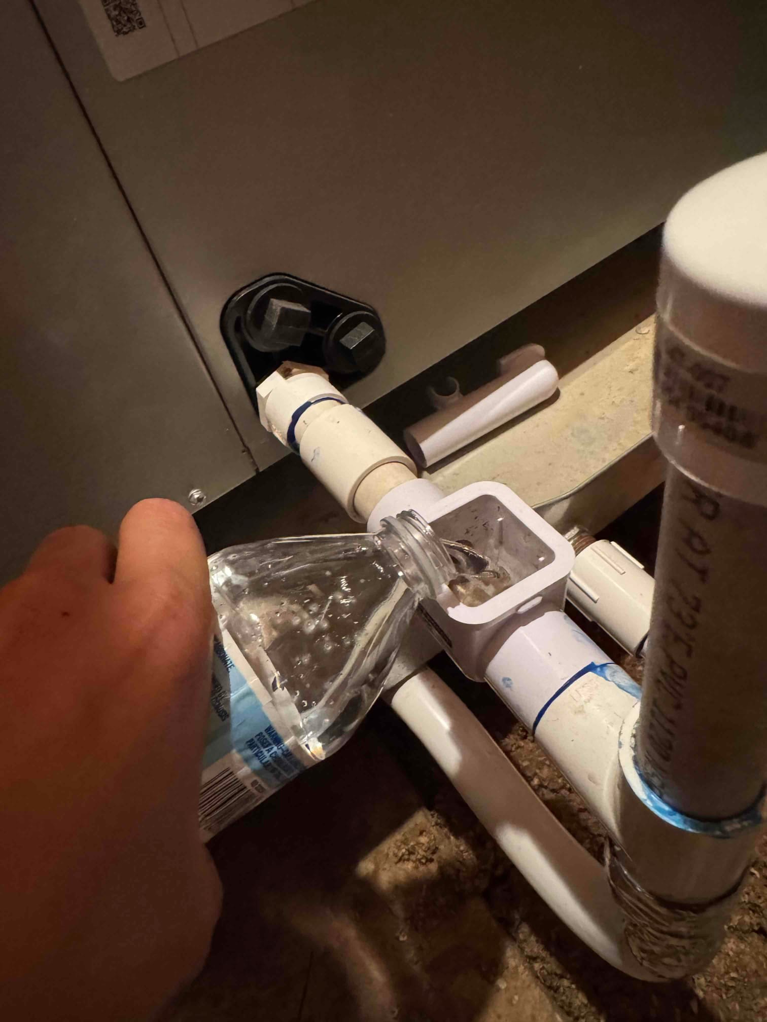 Technician pours cleaning solution into the air handler’s condensate drain tee to flush and clear the drain line.