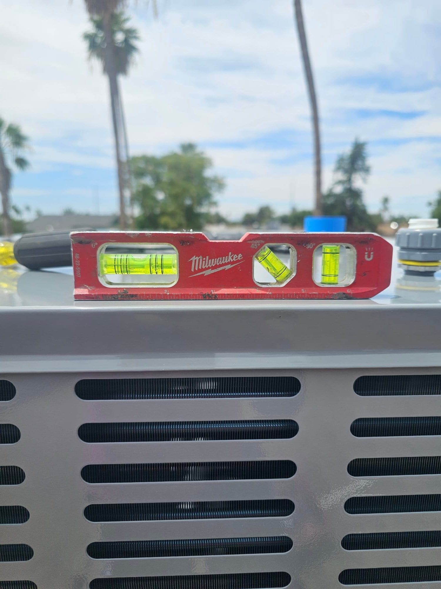 Torpedo level on top of a newly installed outdoor condenser, confirming the unit is set level on its pad.