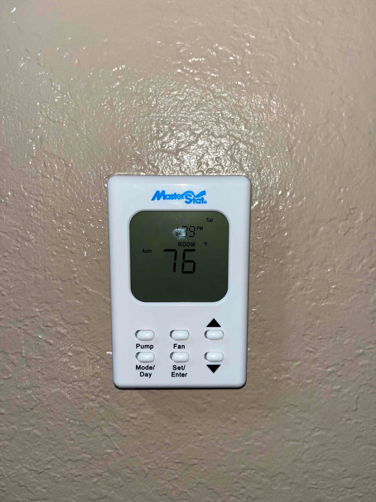 Wall-mounted digital thermostat displays ROOM 76 °F with system set to Auto and fan options below.