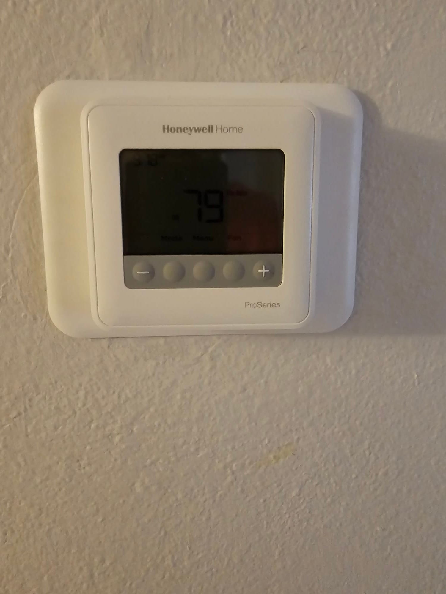 Wall-mounted digital thermostat installed and powered on, displaying a room temperature reading of 79 degrees.