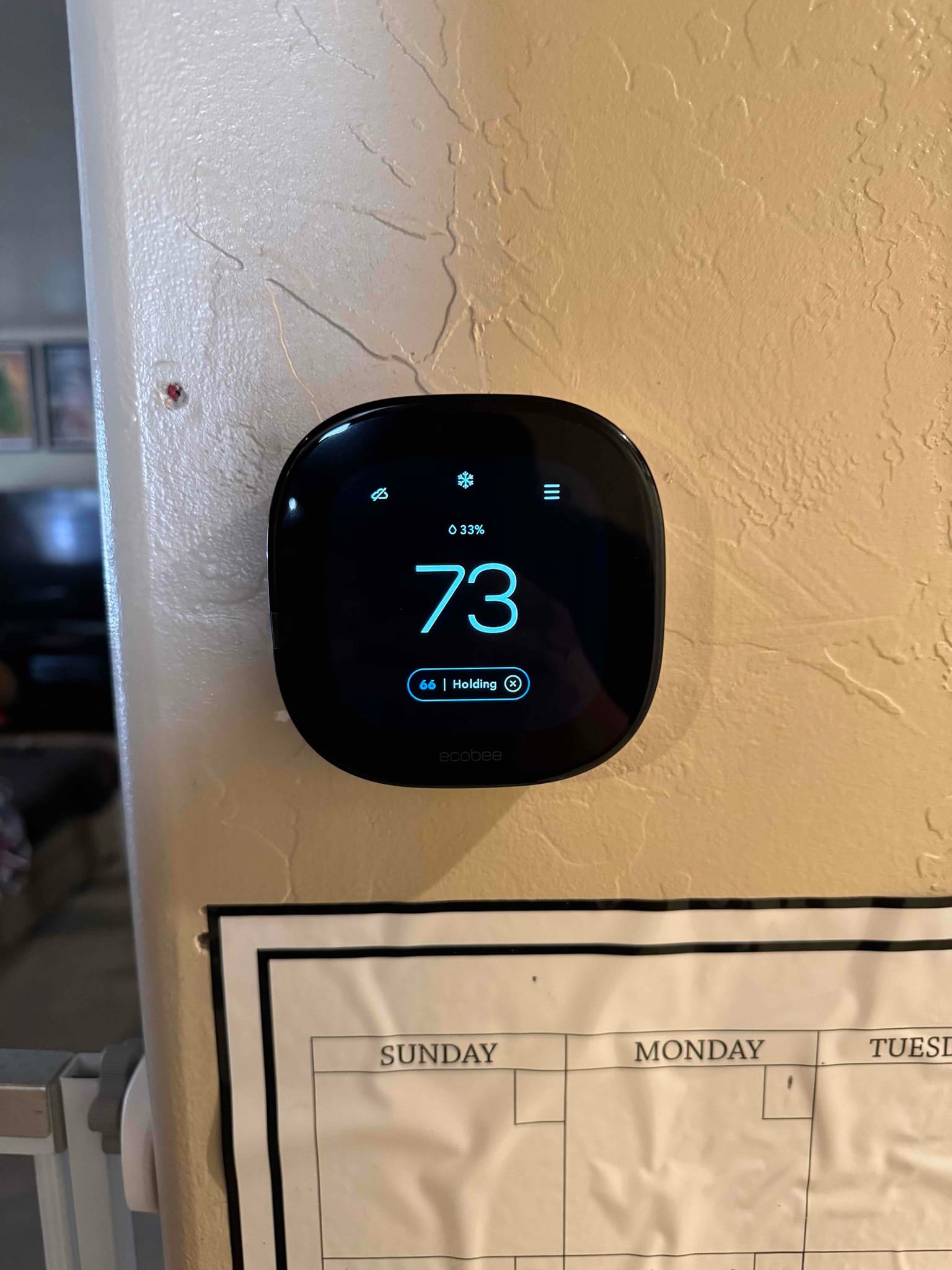 Wall-mounted smart thermostat displays 73 degrees with cooling mode active and a hold setpoint of 66 degrees.