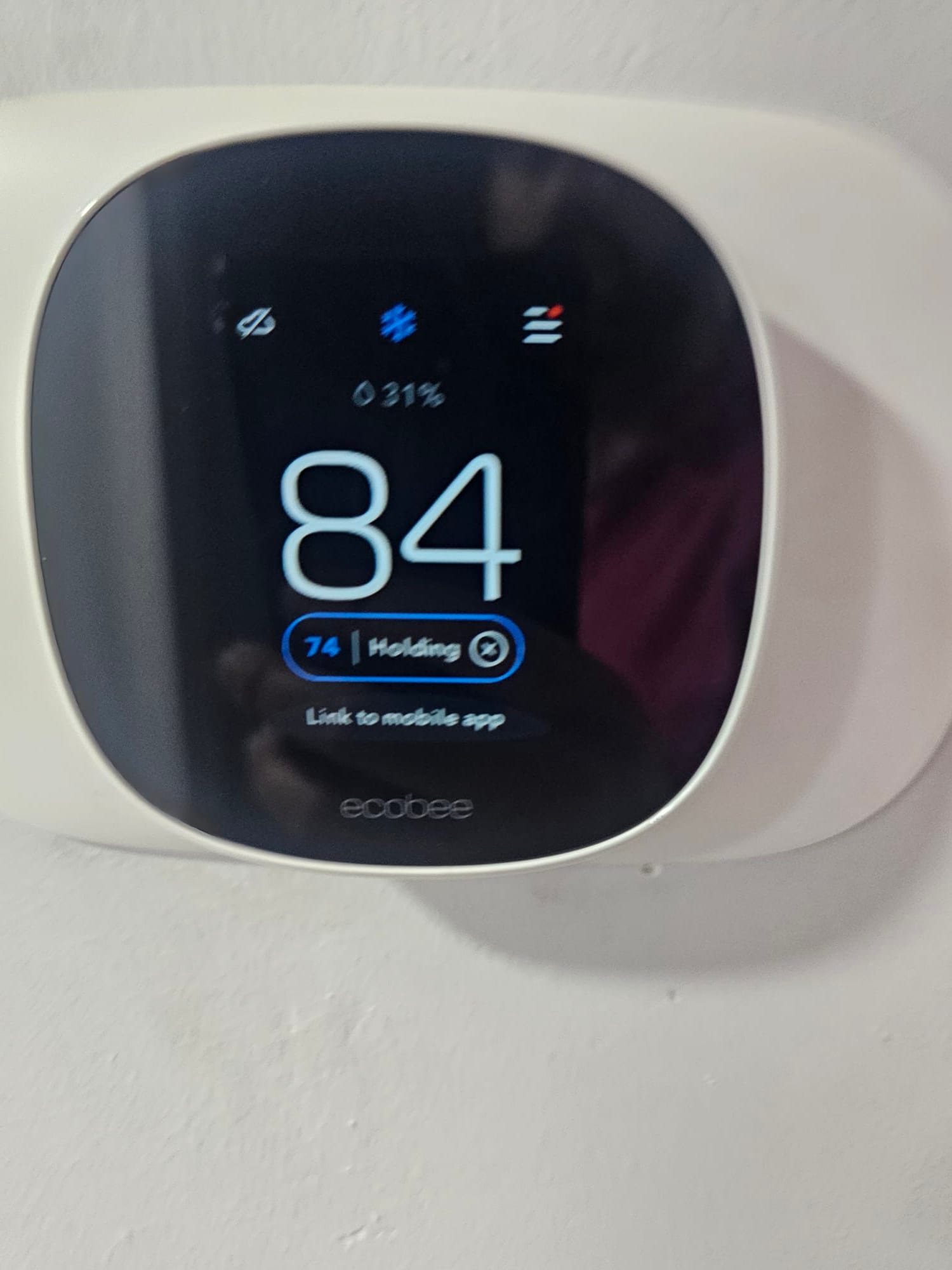 Wall-mounted smart thermostat displays 84 degrees with cooling mode active and a setpoint of 74 on hold.