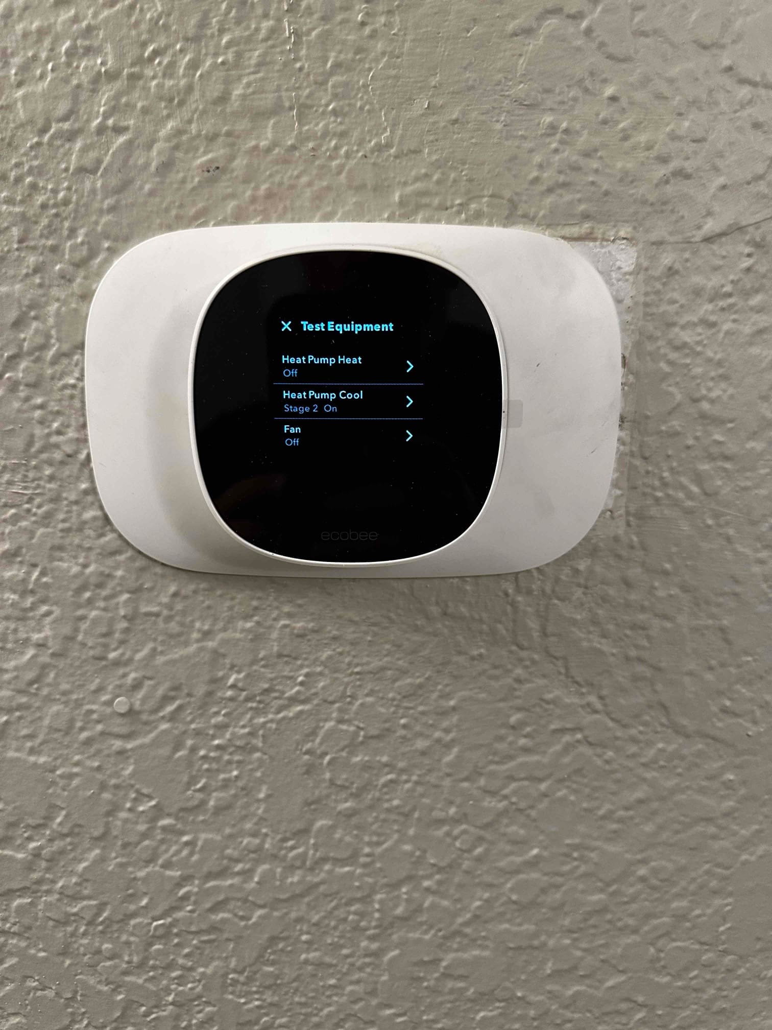 Wall-mounted smart thermostat in test mode showing heat pump cool Stage 2 on and fan off.