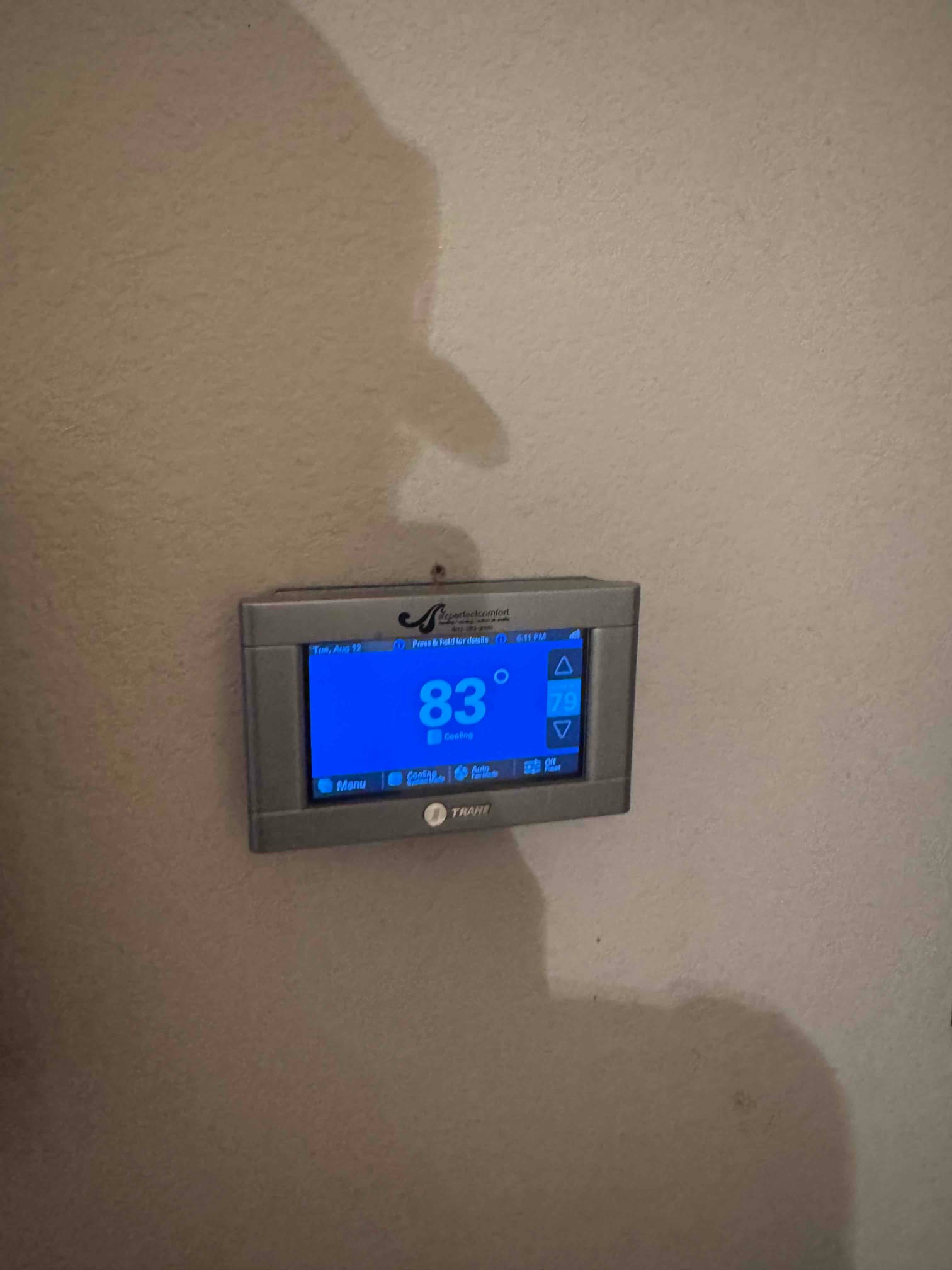Wall-mounted thermostat display shows indoor temperature at 83°F with up and down setpoint controls visible.
