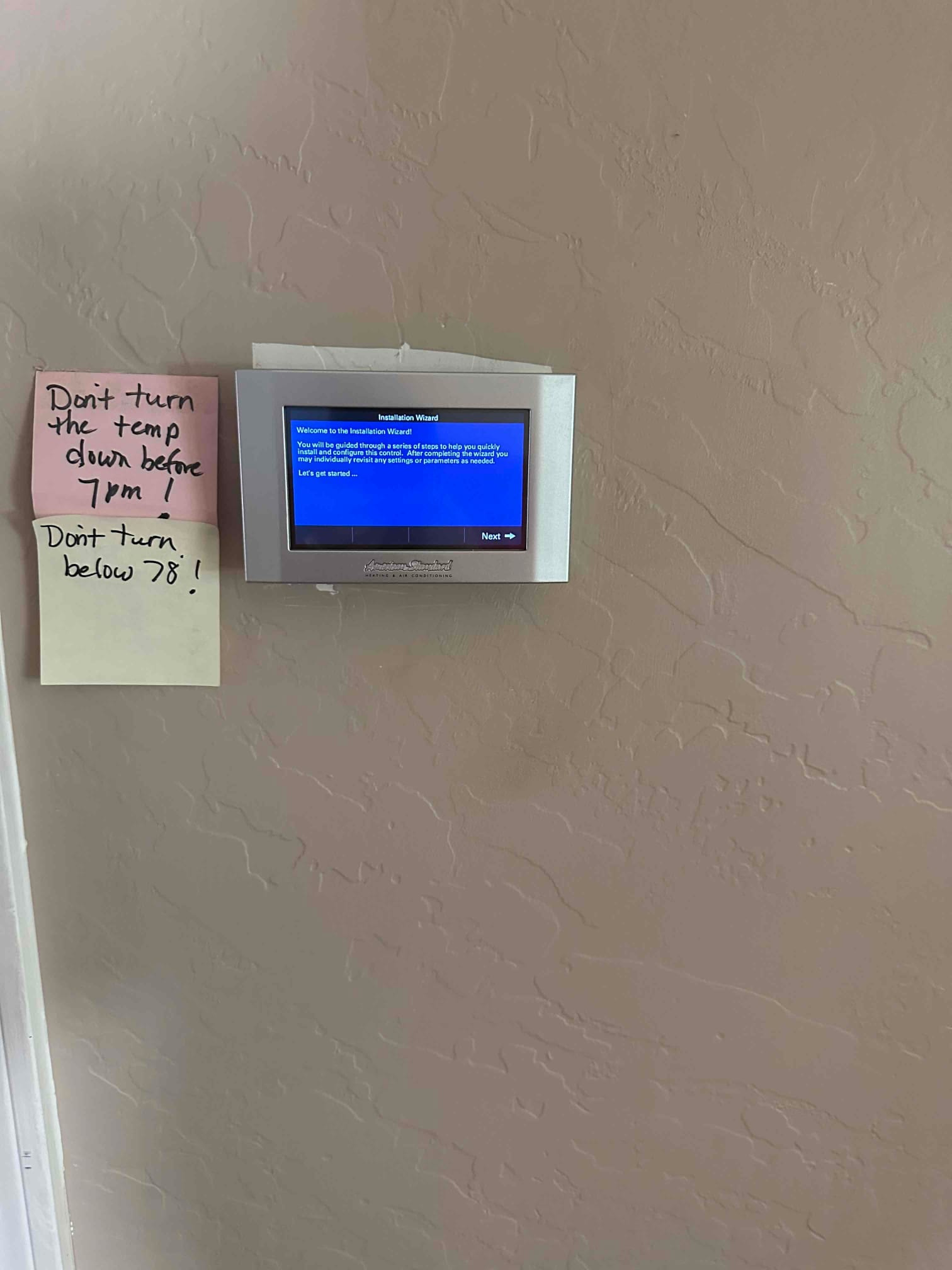 Wall-mounted thermostat displays an installation wizard screen, indicating system setup during a new HVAC installation.