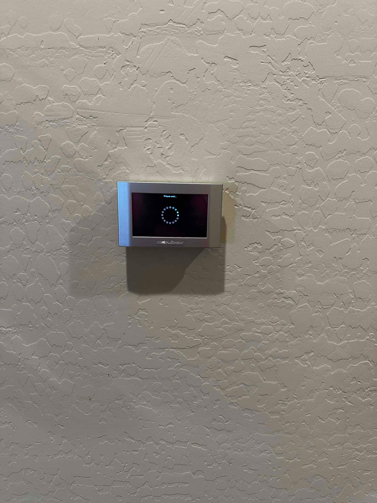 Wall-mounted thermostat displays a loading screen after installation, indicating system startup and control initialization.