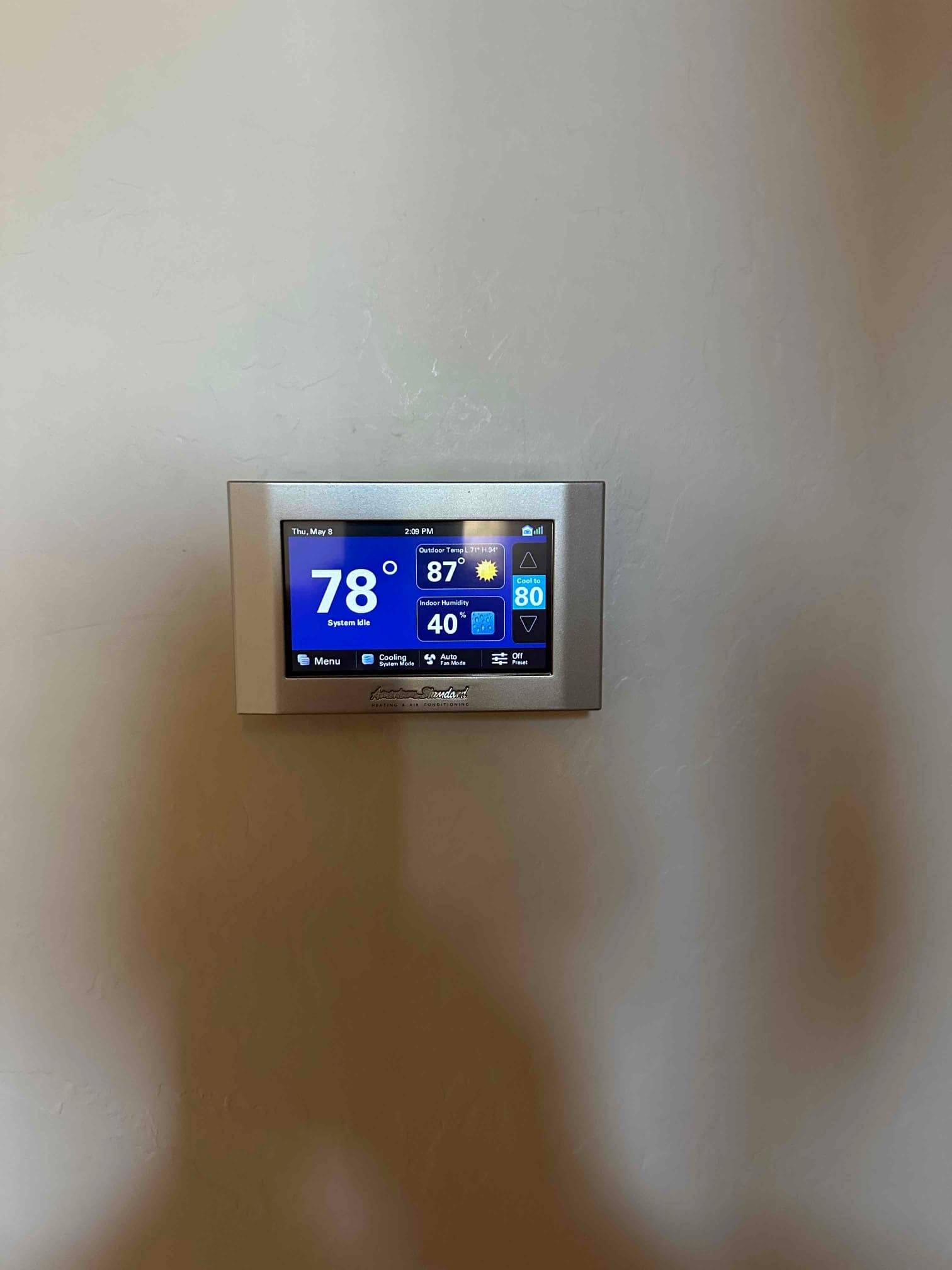Wall-mounted touchscreen thermostat displays indoor temperature of 78 degrees with system status and control options.