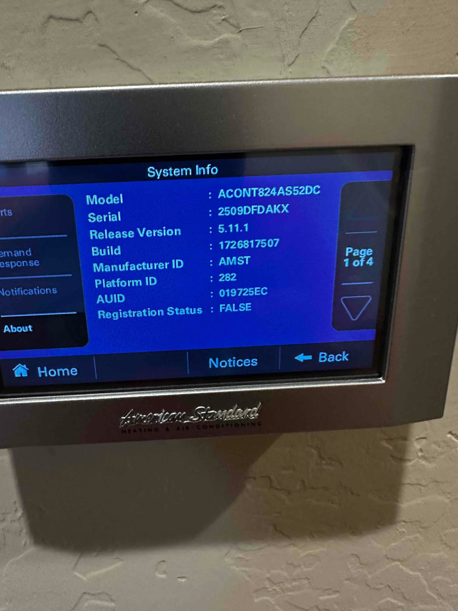 Wall-mounted touchscreen thermostat displays system information menu during setup after installation.