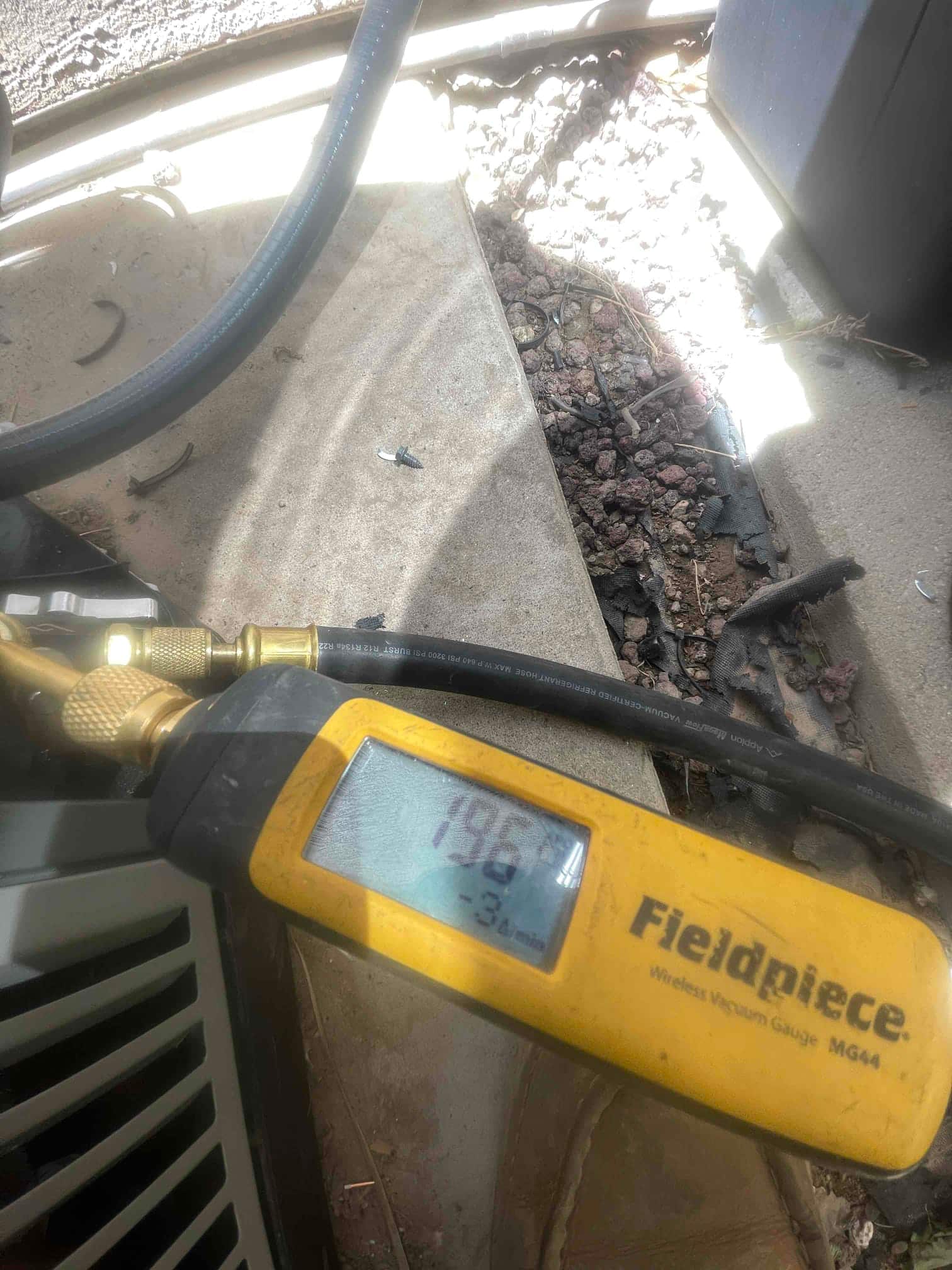 Wireless micron gauge connected at the condenser shows a deep vacuum during system evacuation before refrigerant charging.
