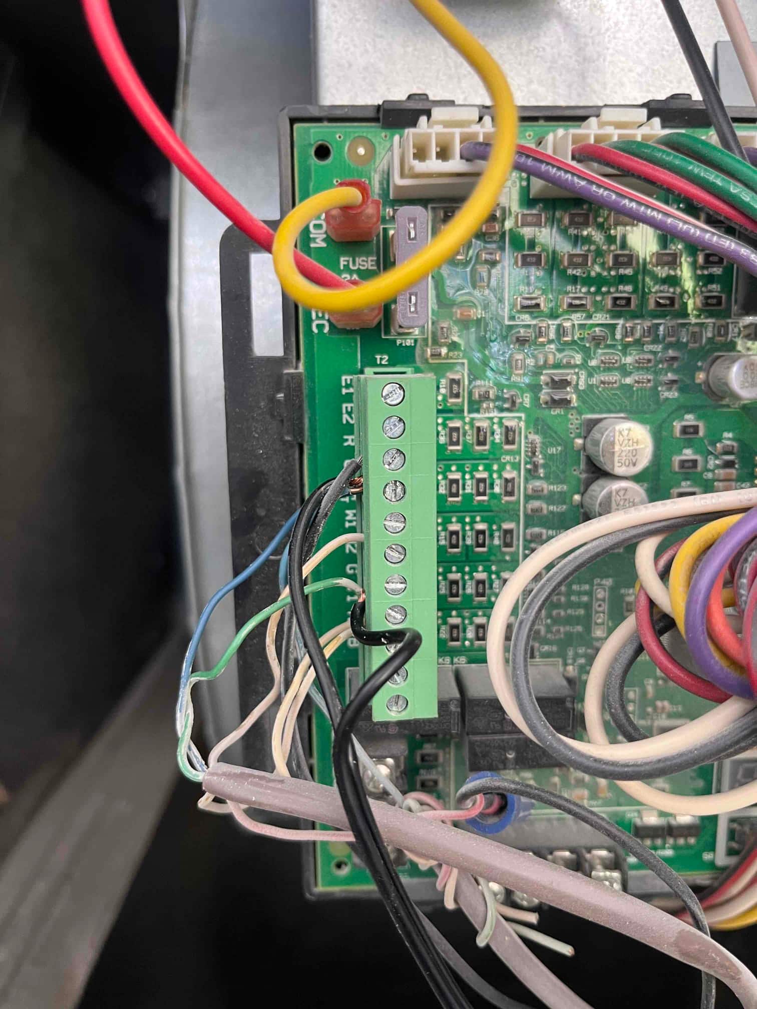 Air handler control board with multiple low-voltage conductors landed on a green terminal strip and an inline 5A fuse visible.