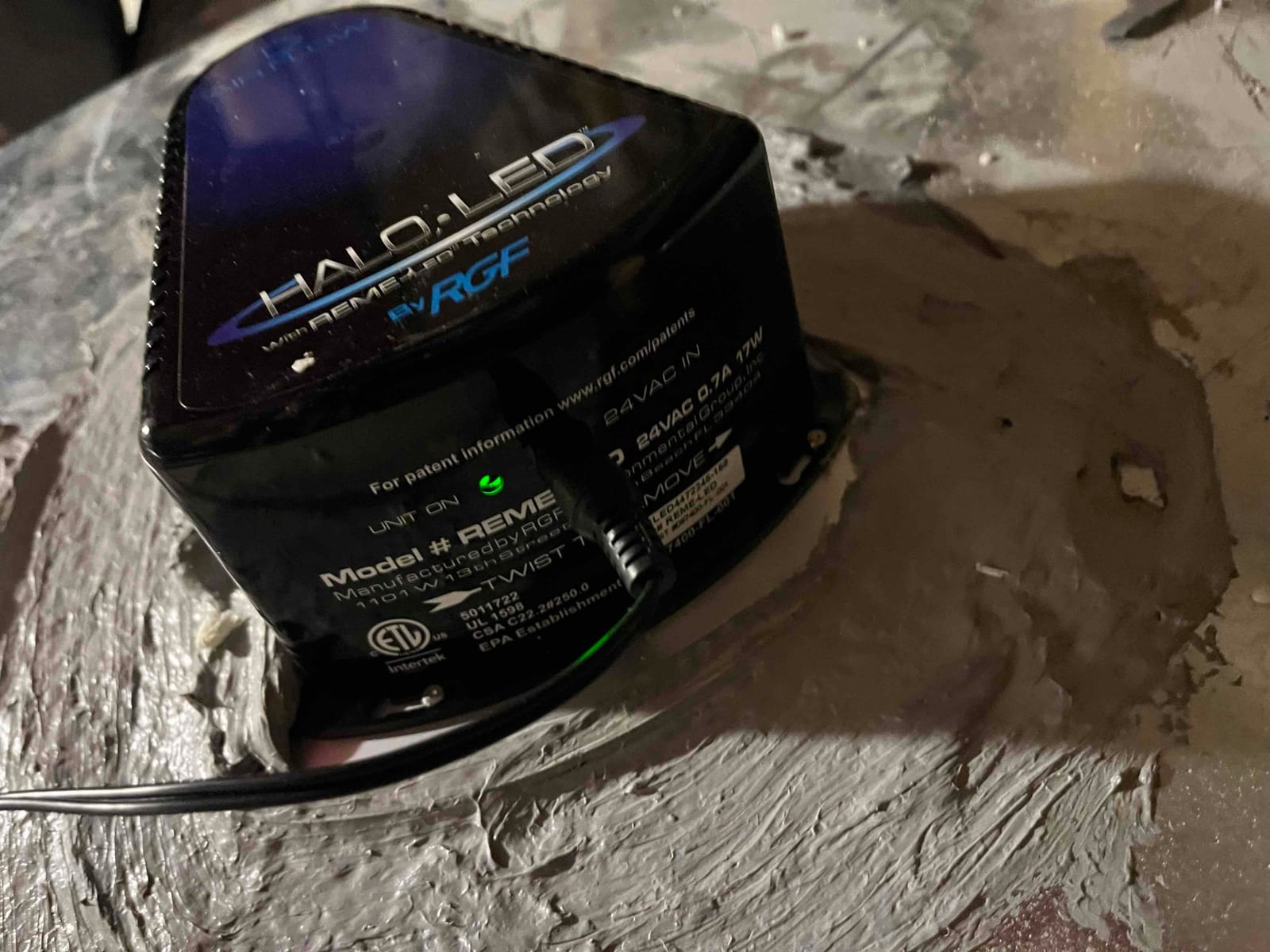 Air purifier module mounted on ductwork with sealant applied around the base and power indicator illuminated.