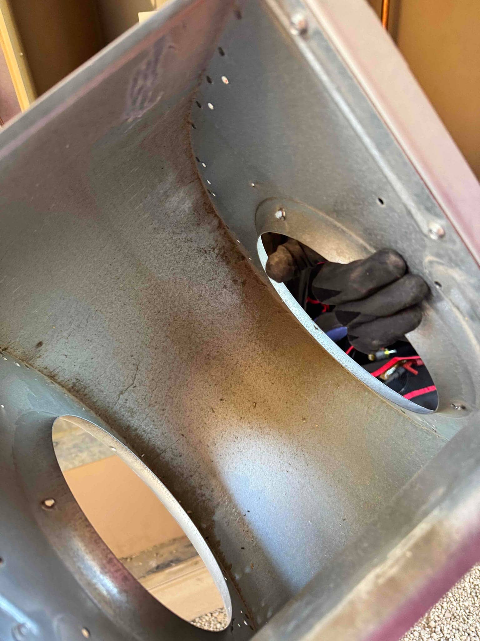 Blower housing removed from the air handler, showing interior surface debris before cleaning during blower assembly service.