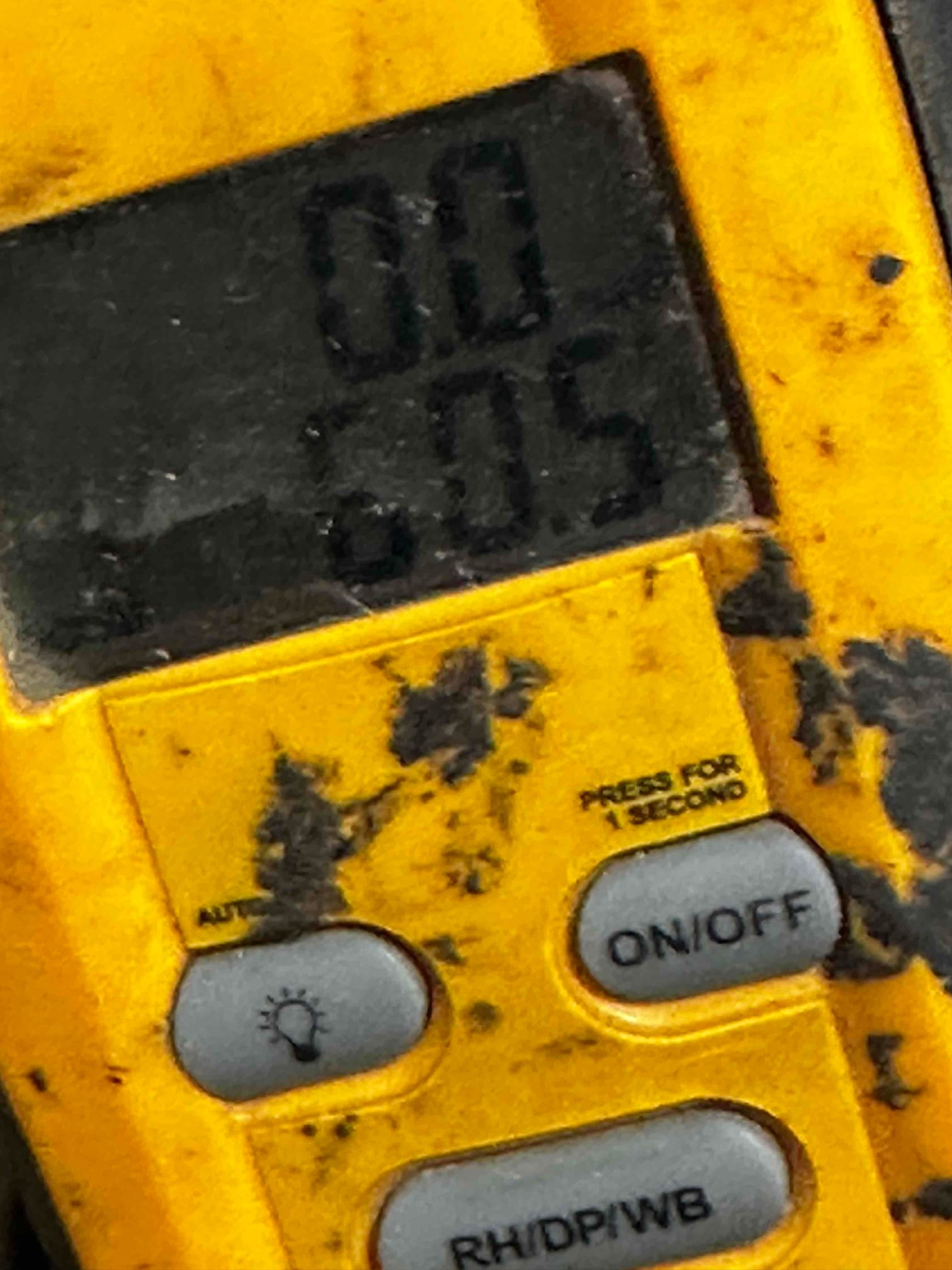 Close-up of a handheld digital thermometer displaying a temperature reading used for air-side commissioning.
