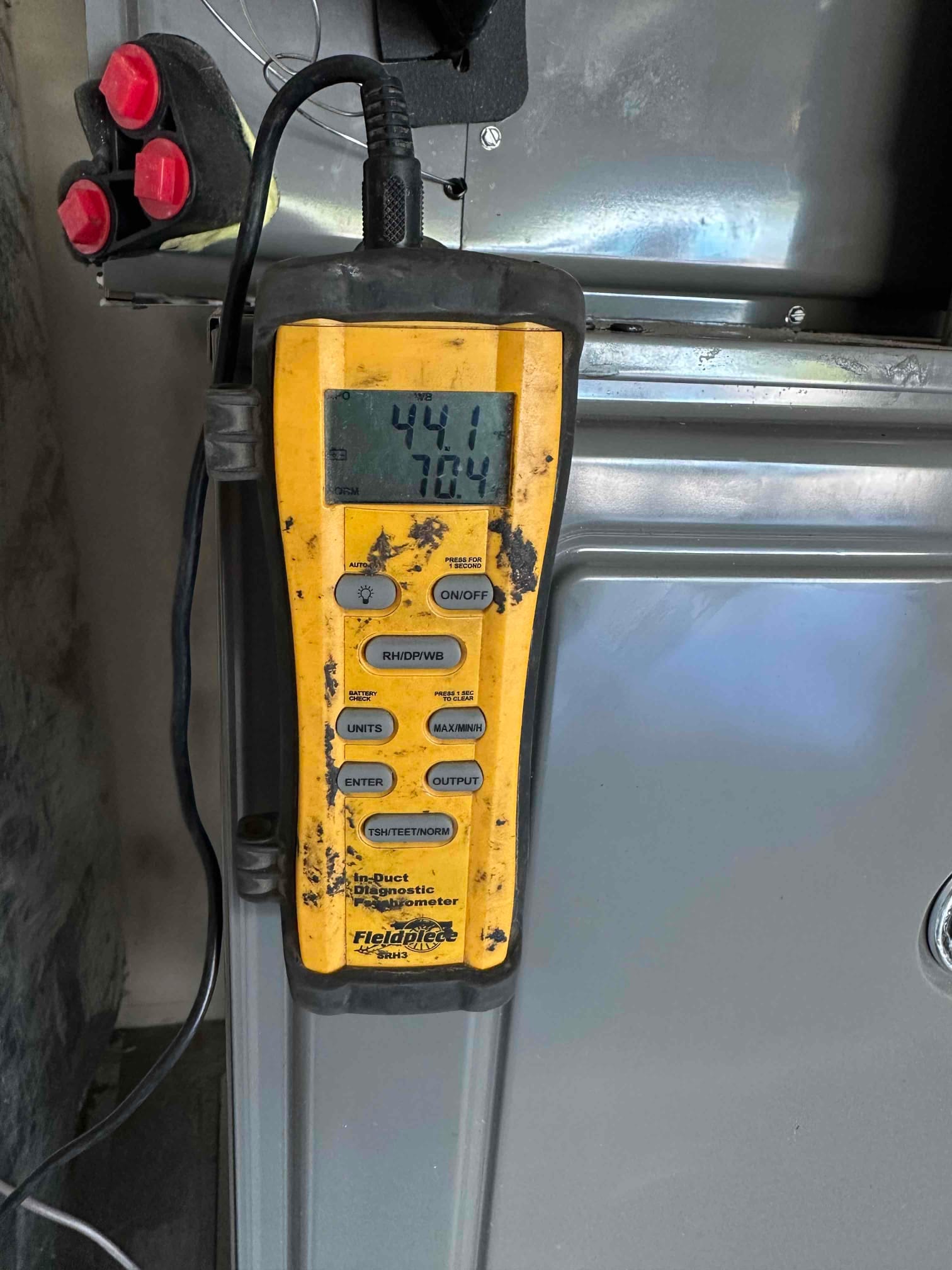 Digital in-duct thermometer displays 70.4 degrees Fahrenheit return air temperature during HVAC commissioning at the air handler cabinet.