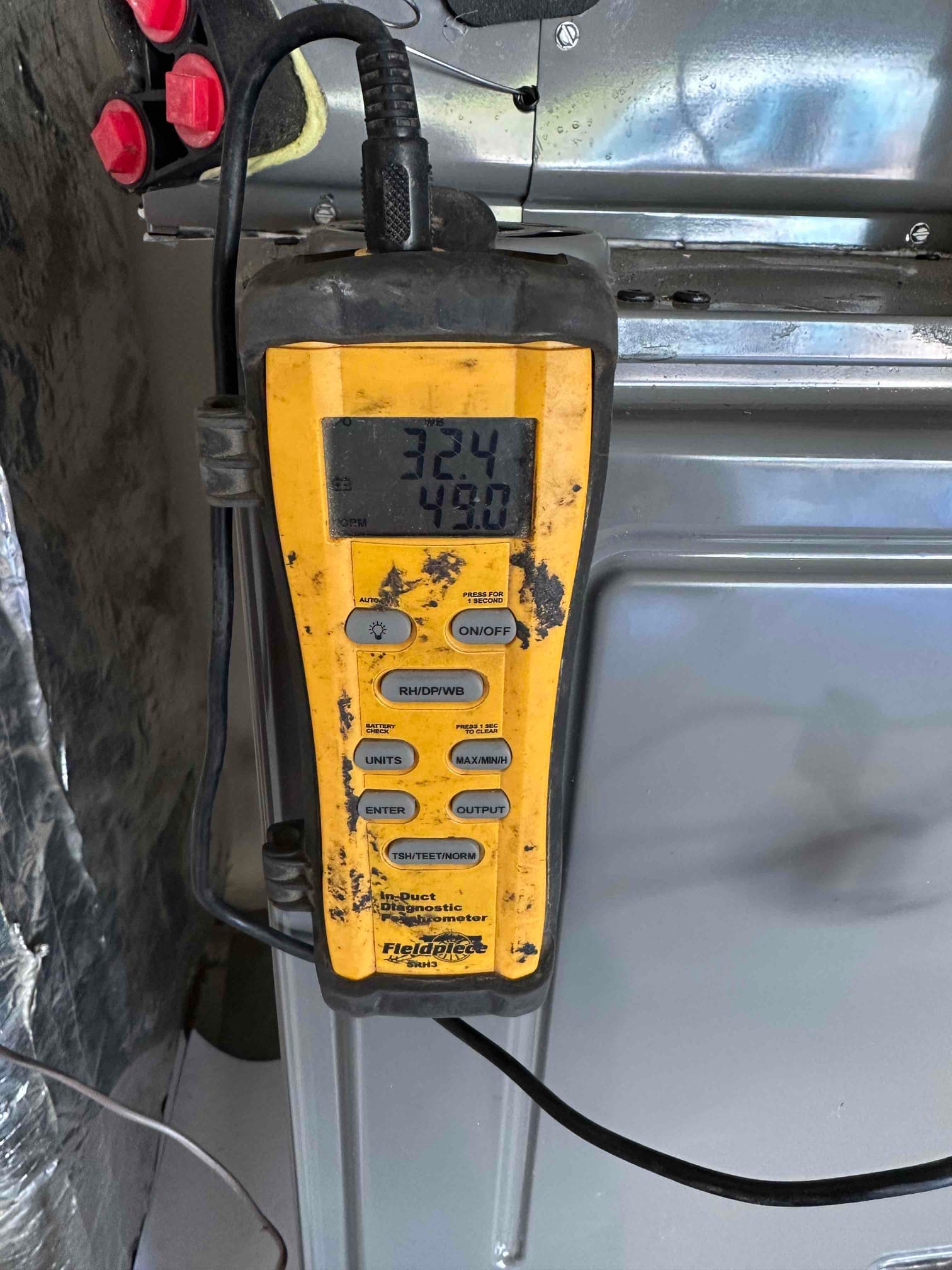 Digital in-duct thermometer and hygrometer measures air conditions at the new system, with display readings visible on the screen.