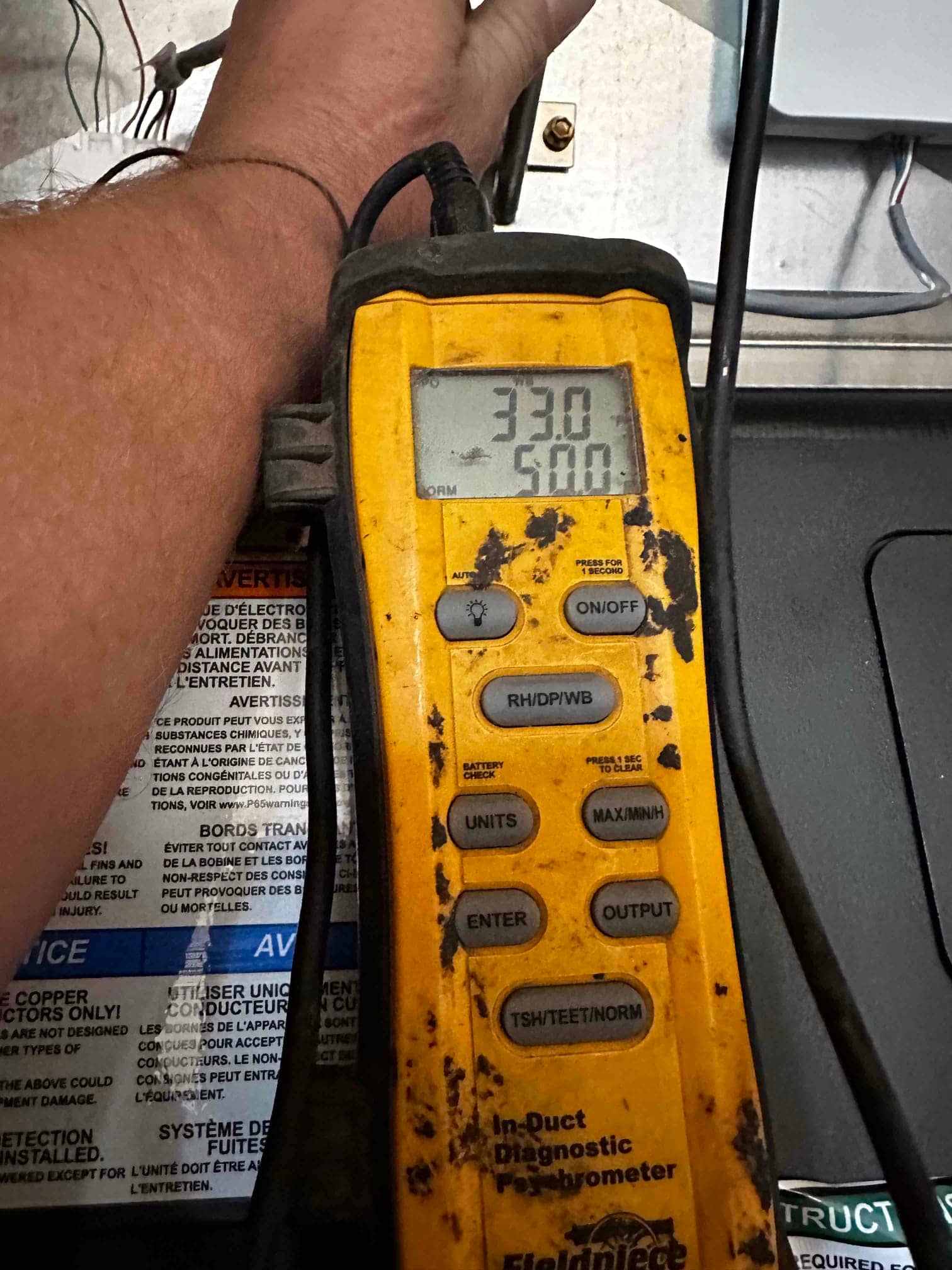 Digital in-duct thermometer shows 55.0 degrees Fahrenheit on the supply side during cooling performance check.