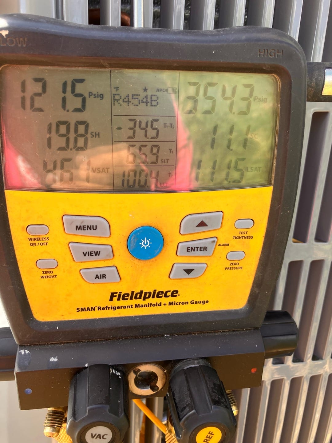 Digital manifold connected to the condenser shows operating pressures with refrigerant type R-454B during system commissioning.
