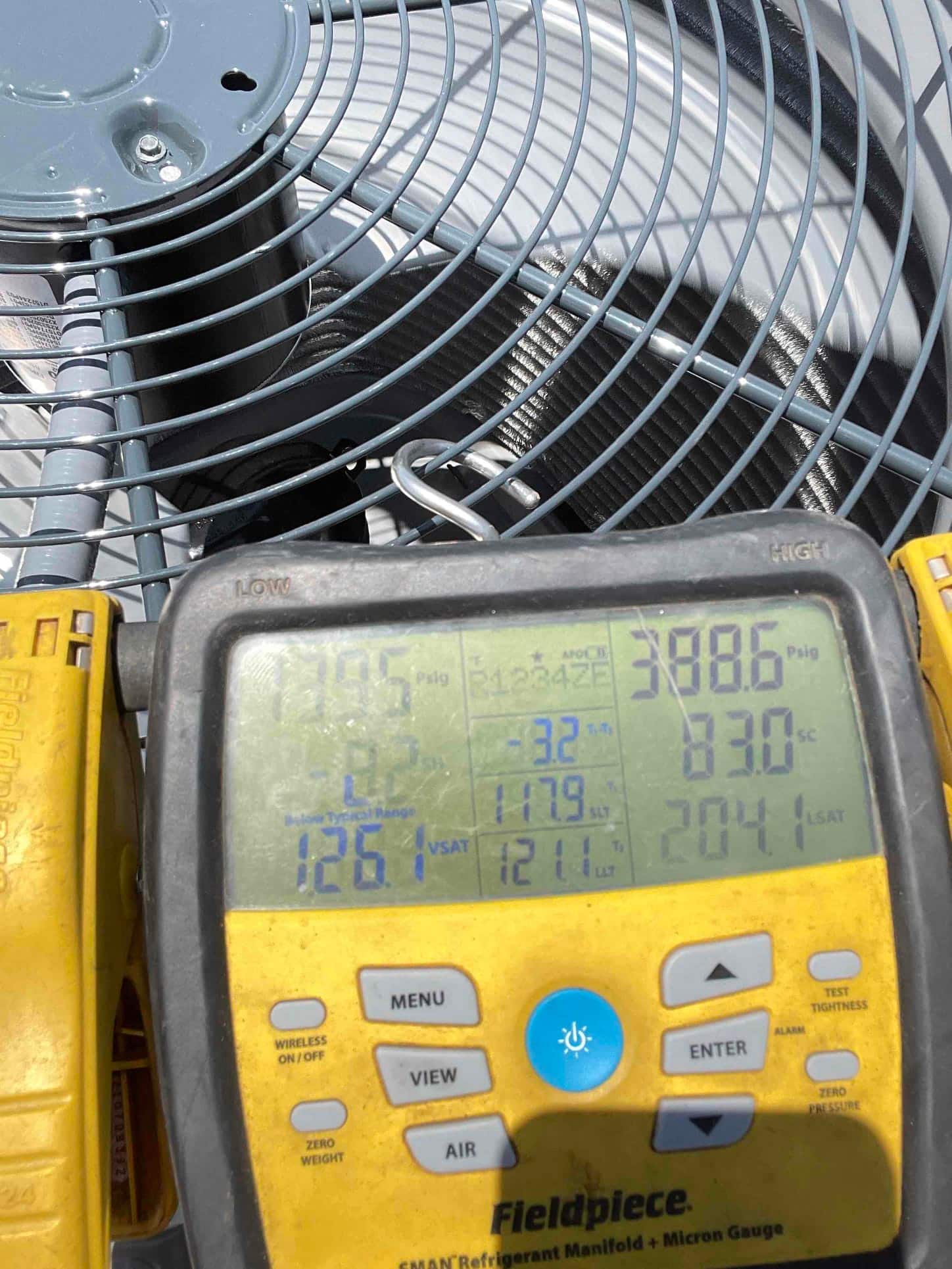 Digital manifold connected at the outdoor unit shows operating suction and liquid pressures while the heat pump runs.