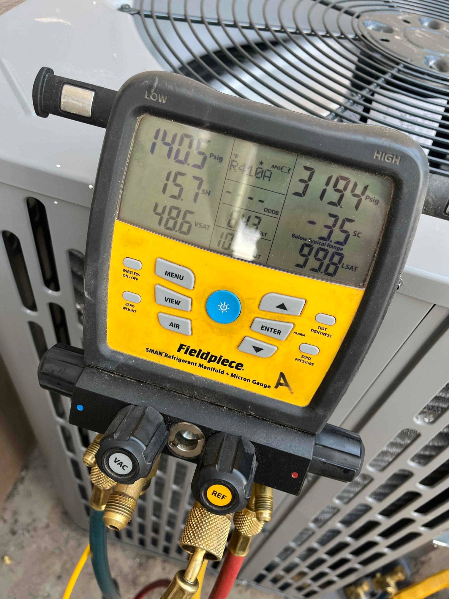 Digital manifold connected to the outdoor unit shows operating pressures with displayed superheat and subcooling during system commissioning.