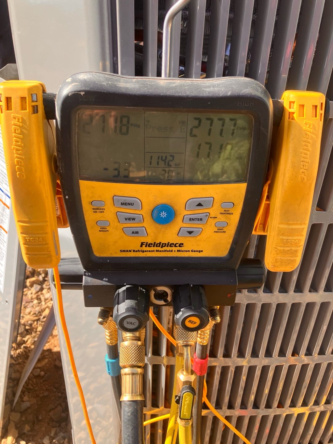 Digital manifold connected to the outdoor unit shows operating suction and liquid pressures during system commissioning.