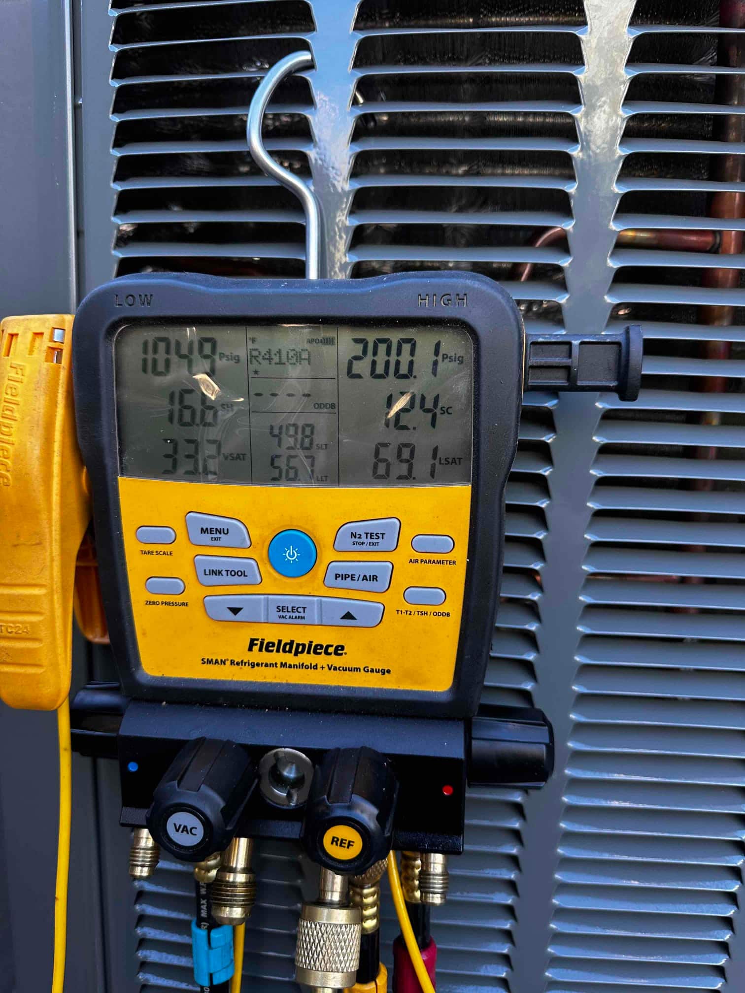 Digital manifold gauges on the condenser show operating pressures with R-410A selected during system commissioning.