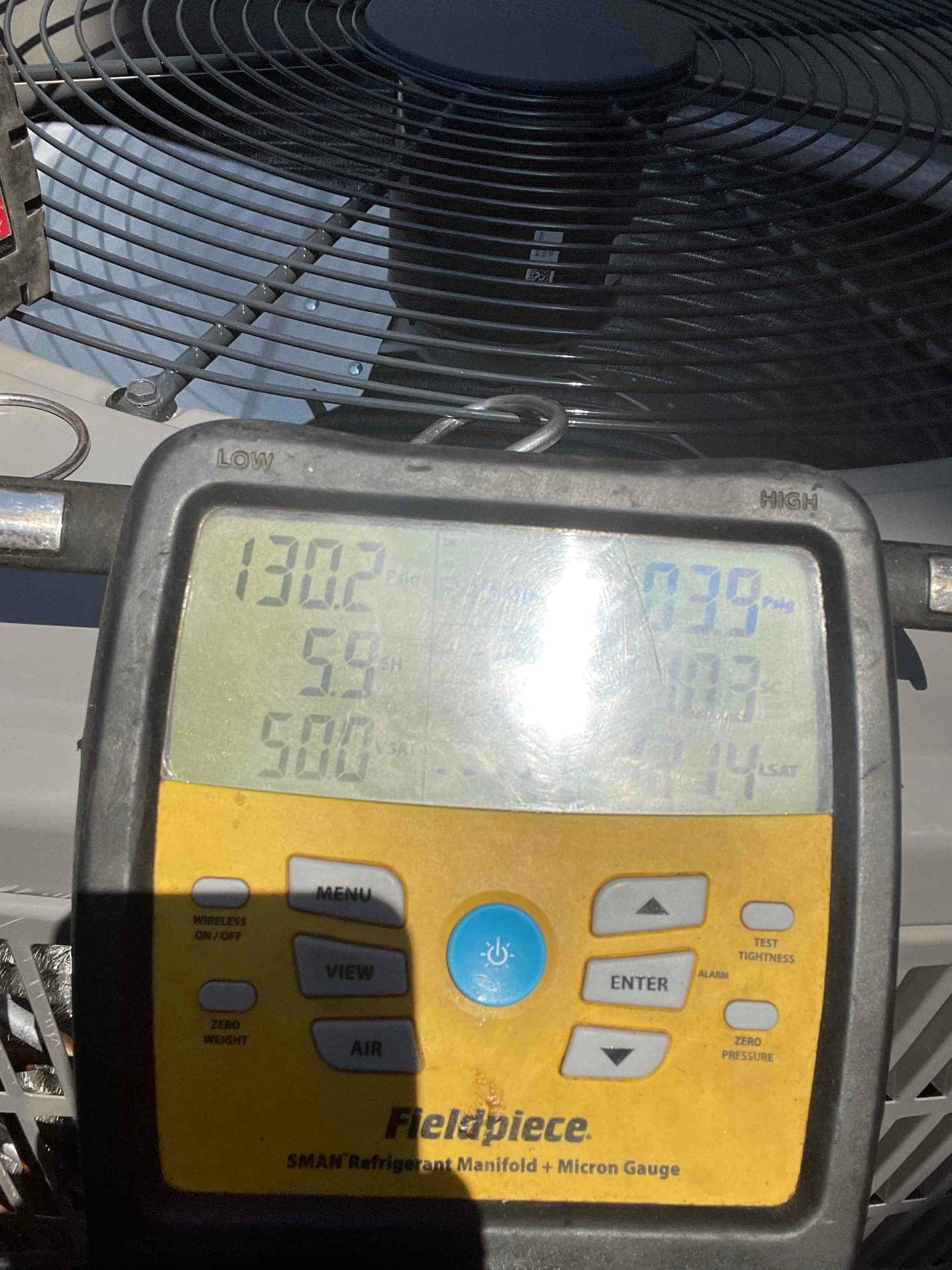 Digital manifold on the outdoor unit shows operating refrigerant pressures with the system running during post-install commissioning.
