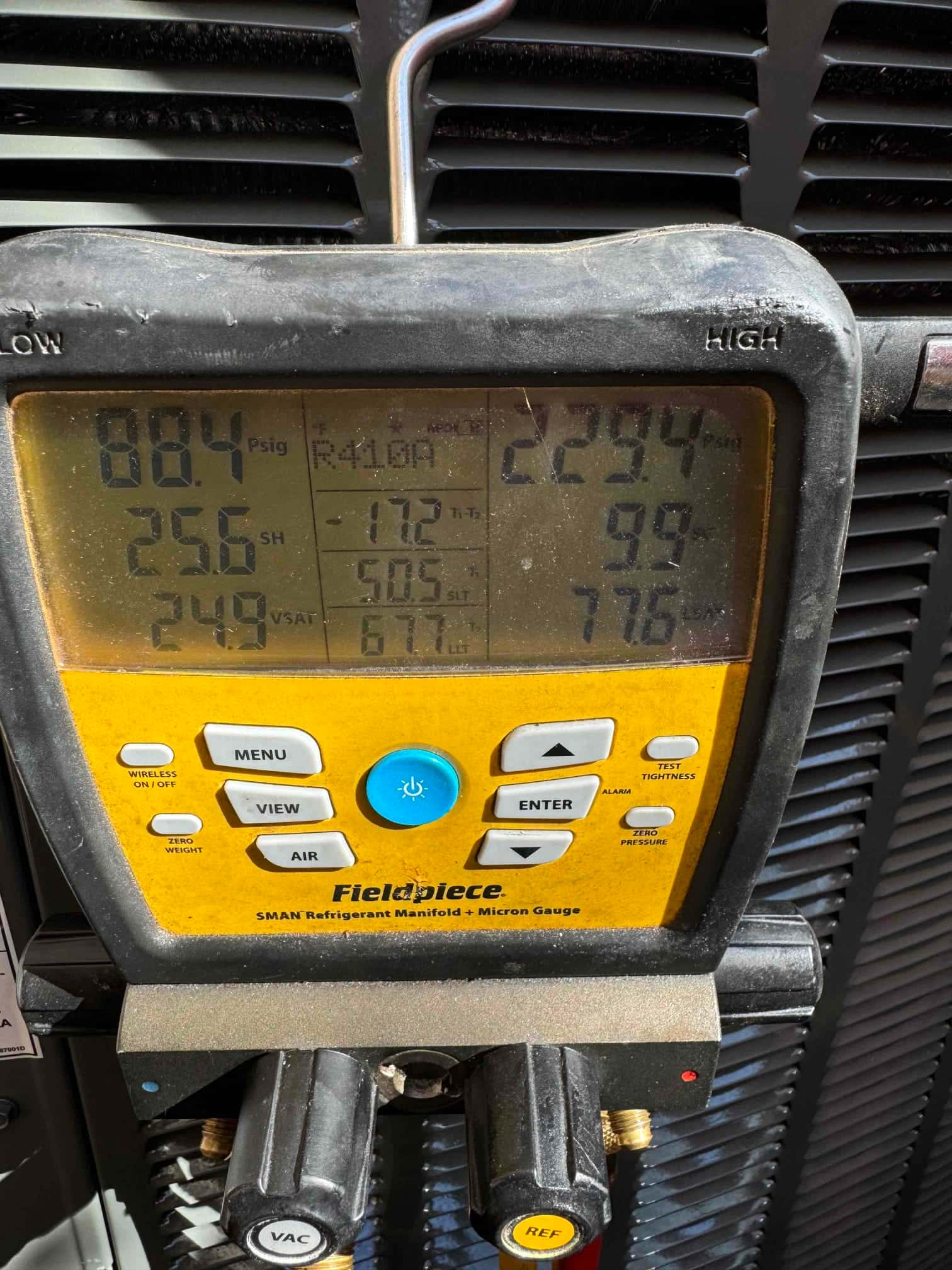 Digital manifold shows operating pressures with R‑410A selected, indicating system running during refrigerant commissioning measurements.