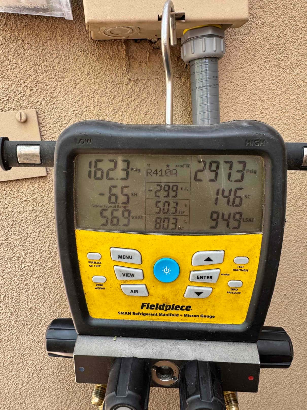 Digital manifold shows operating pressures during system start-up, with suction at 162 psig and liquid at 297 psig, refrigerant R-410A.