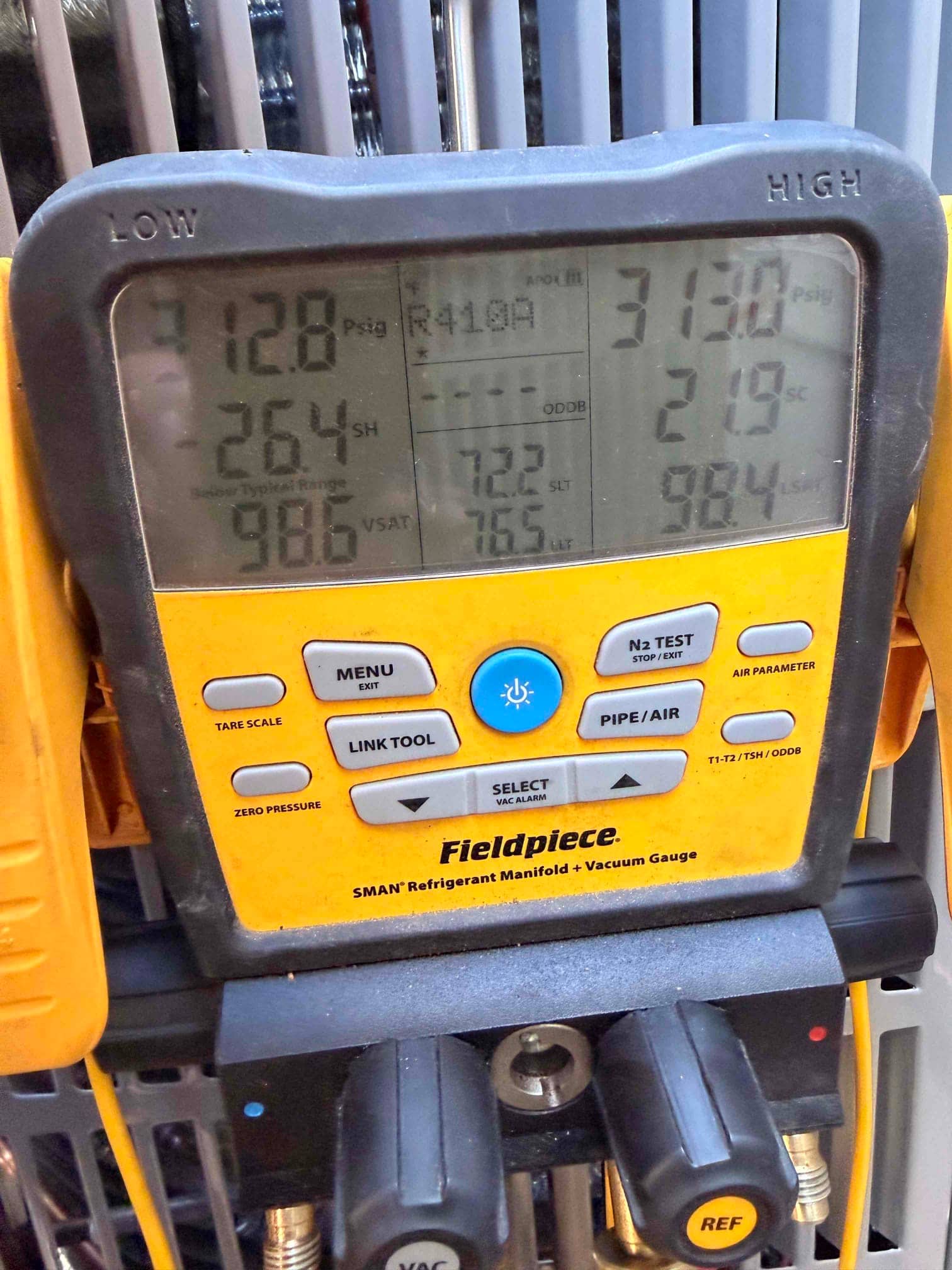 Digital manifold shows system operating pressures with low side at 128 PSI and high side at 313 PSI during commissioning.